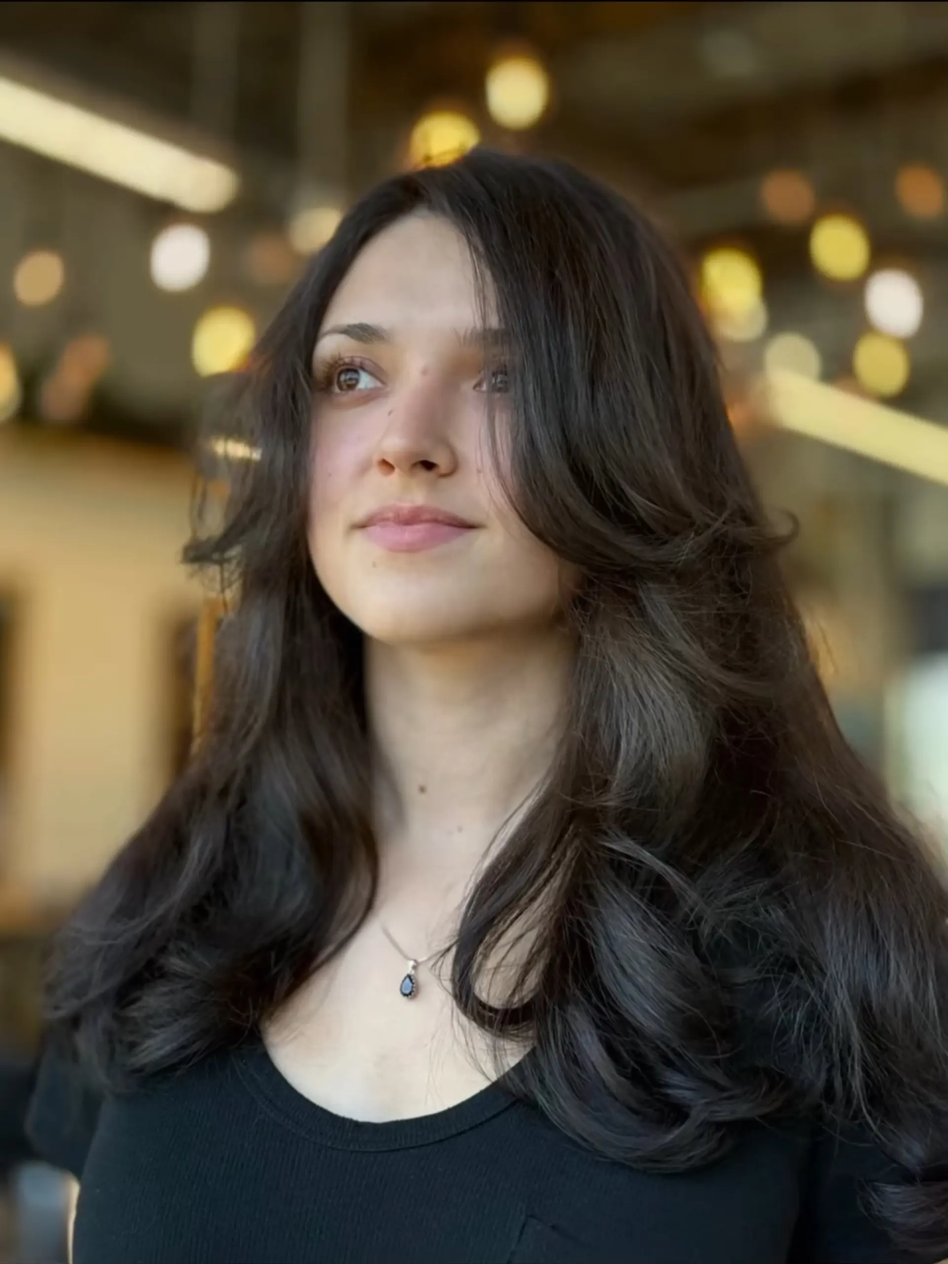 Long, rich dark brown hair styled with voluminous face-framing layers and curtain bangs. 1