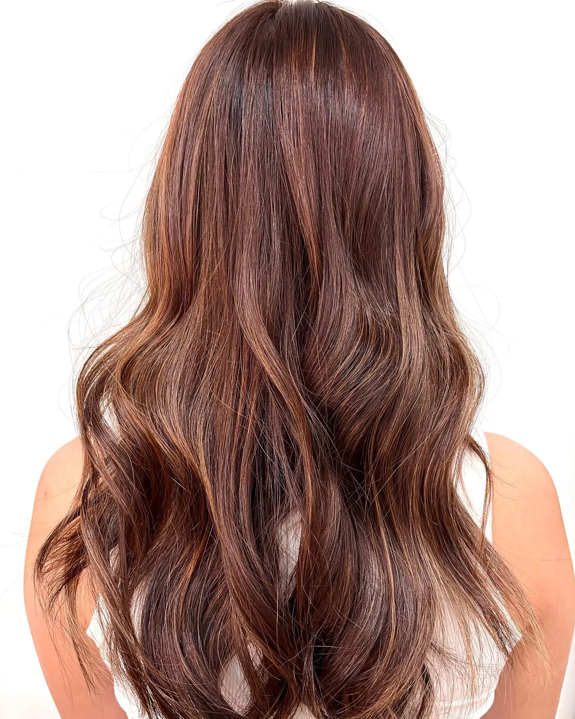 Long warm chestnut brown hair styled in soft, cascading waves with dimensional subtle highlights. 1