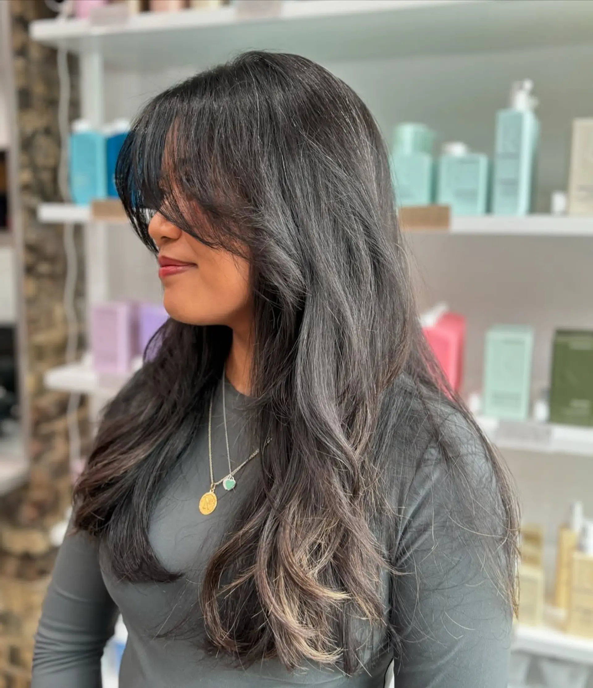 A long, layered haircut styled with soft waves, providing volume and movement. It is complemented by face-framing curtain bangs that blend seamlessly into the layers. 1