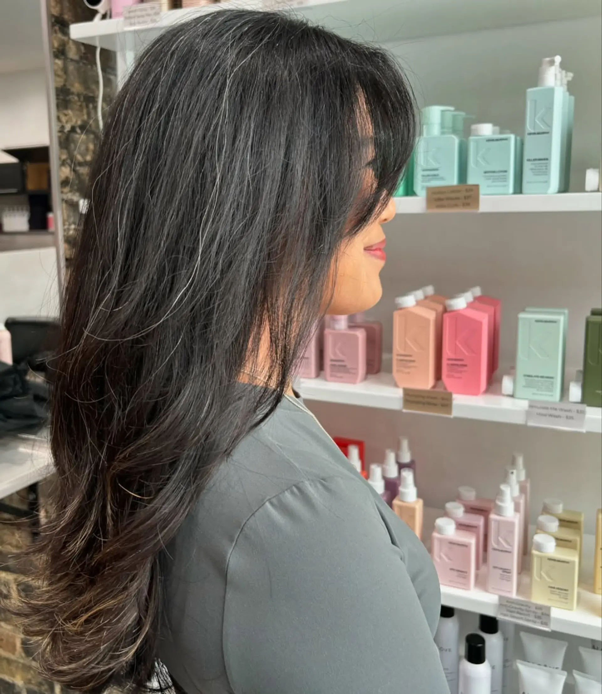 A long, layered haircut styled with soft waves, providing volume and movement. It is complemented by face-framing curtain bangs that blend seamlessly into the layers. 2