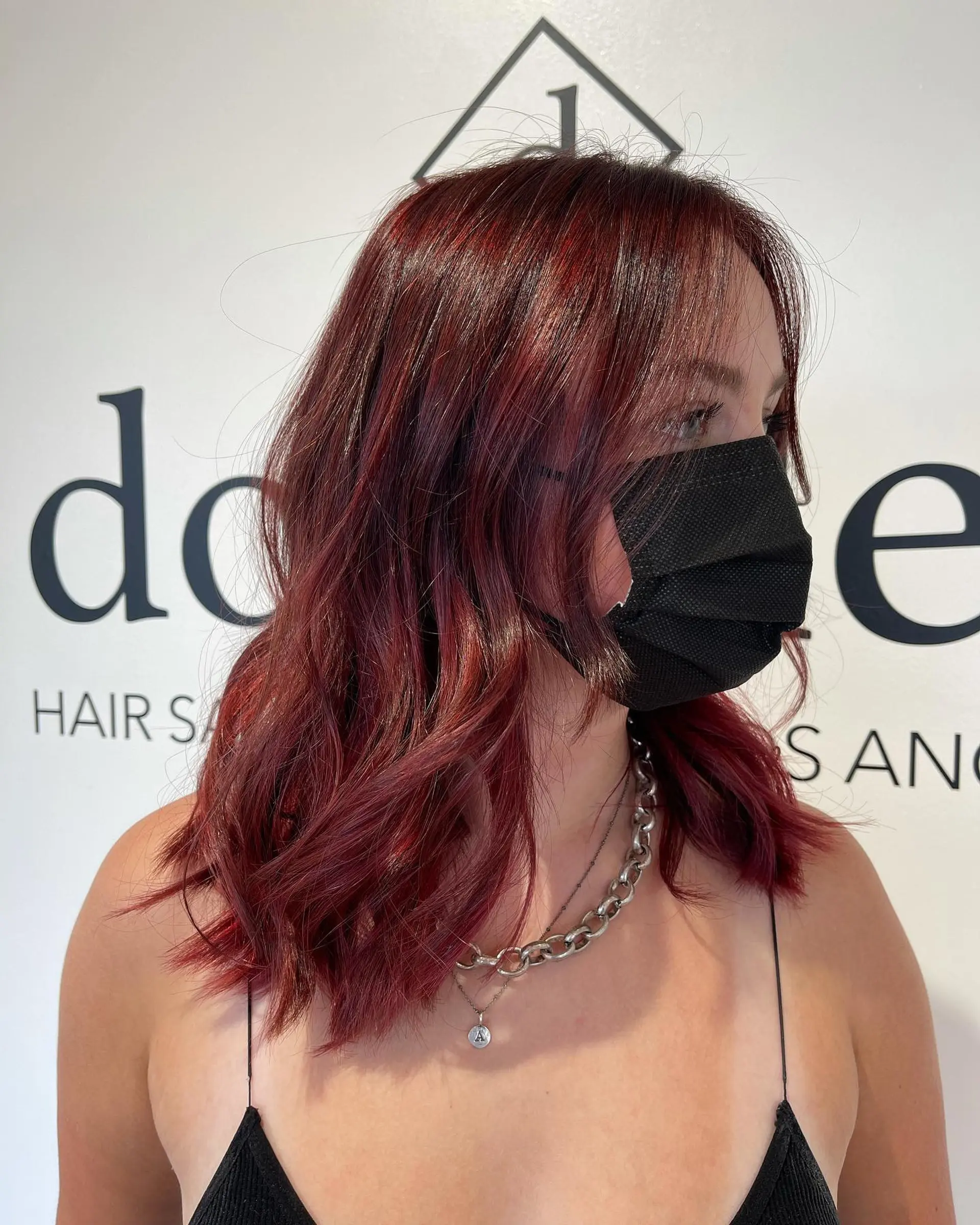 Collarbone-length textured long bob dyed in a vibrant crimson auburn shade, styled with relaxed waves and soft face-framing pieces. 1