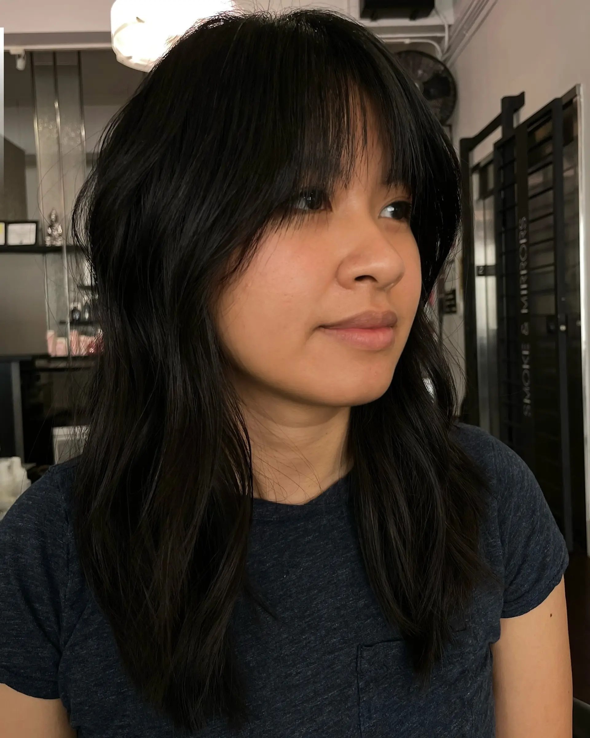 Medium-length dark hair styled with soft, face-framing layers and a full wispy fringe. 1