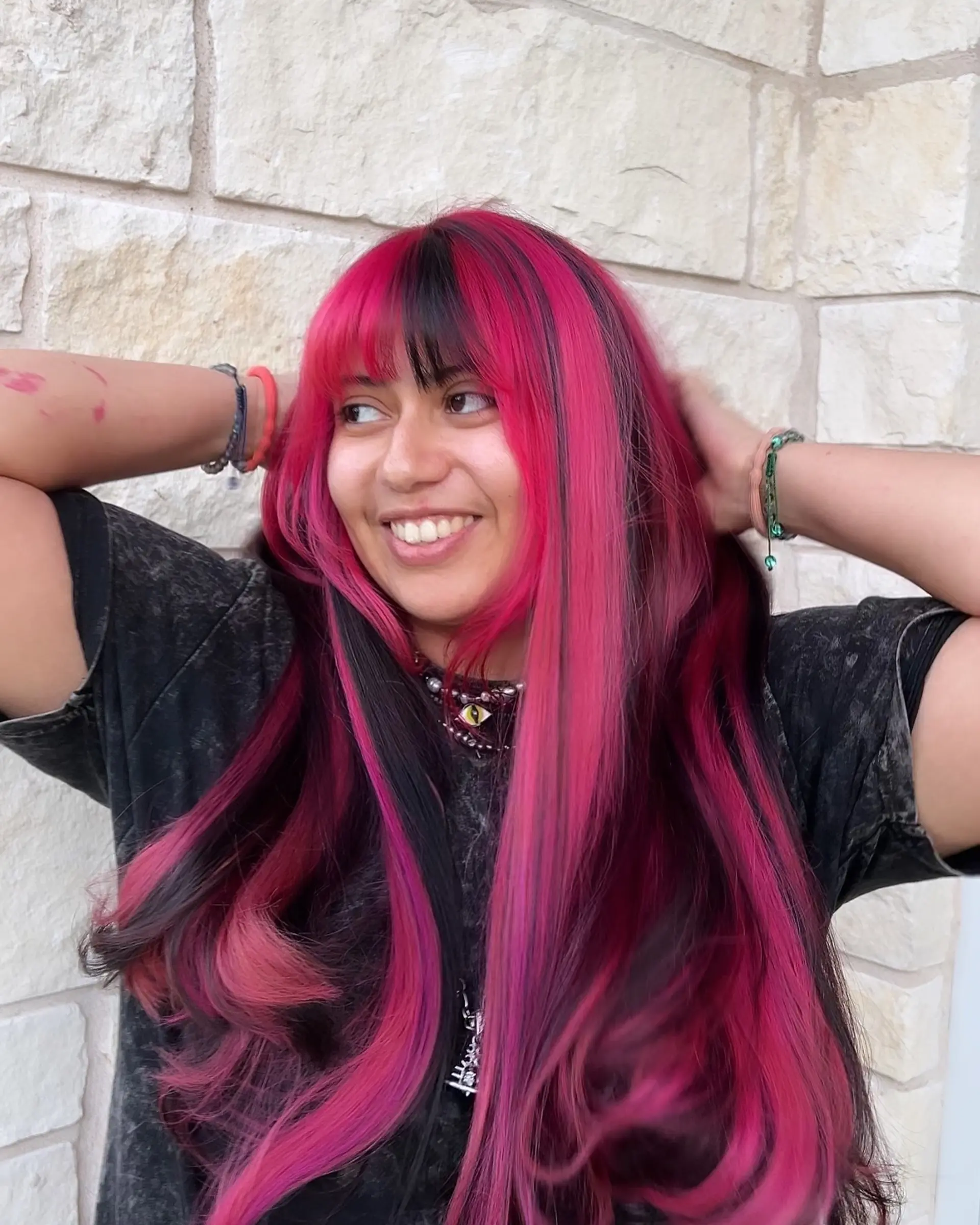 A bold, two-toned style featuring very long, straight hair with hot pink and black sections, complete with full, blunt bangs and face-framing layers. 1