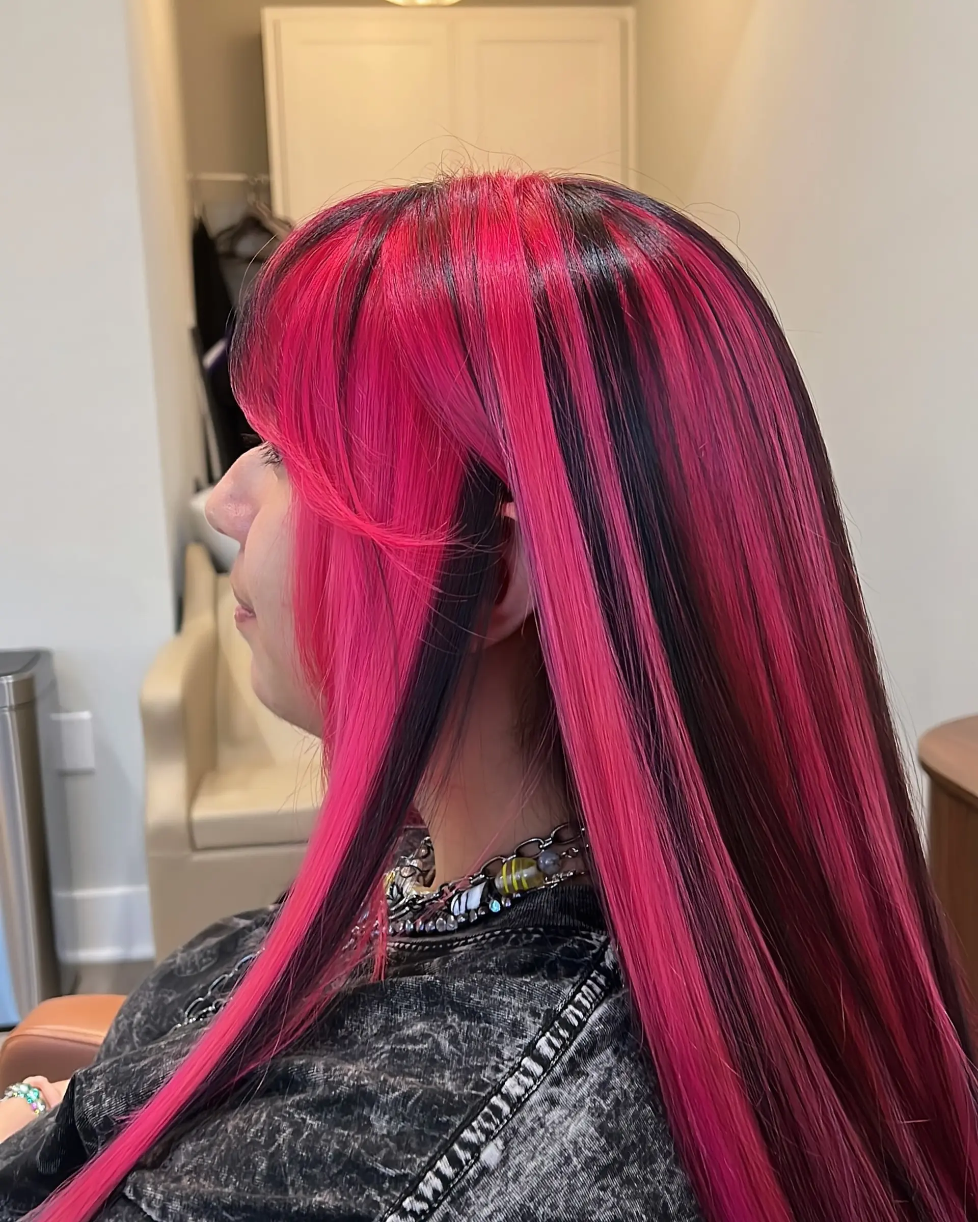 A bold, two-toned style featuring very long, straight hair with hot pink and black sections, complete with full, blunt bangs and face-framing layers. 3