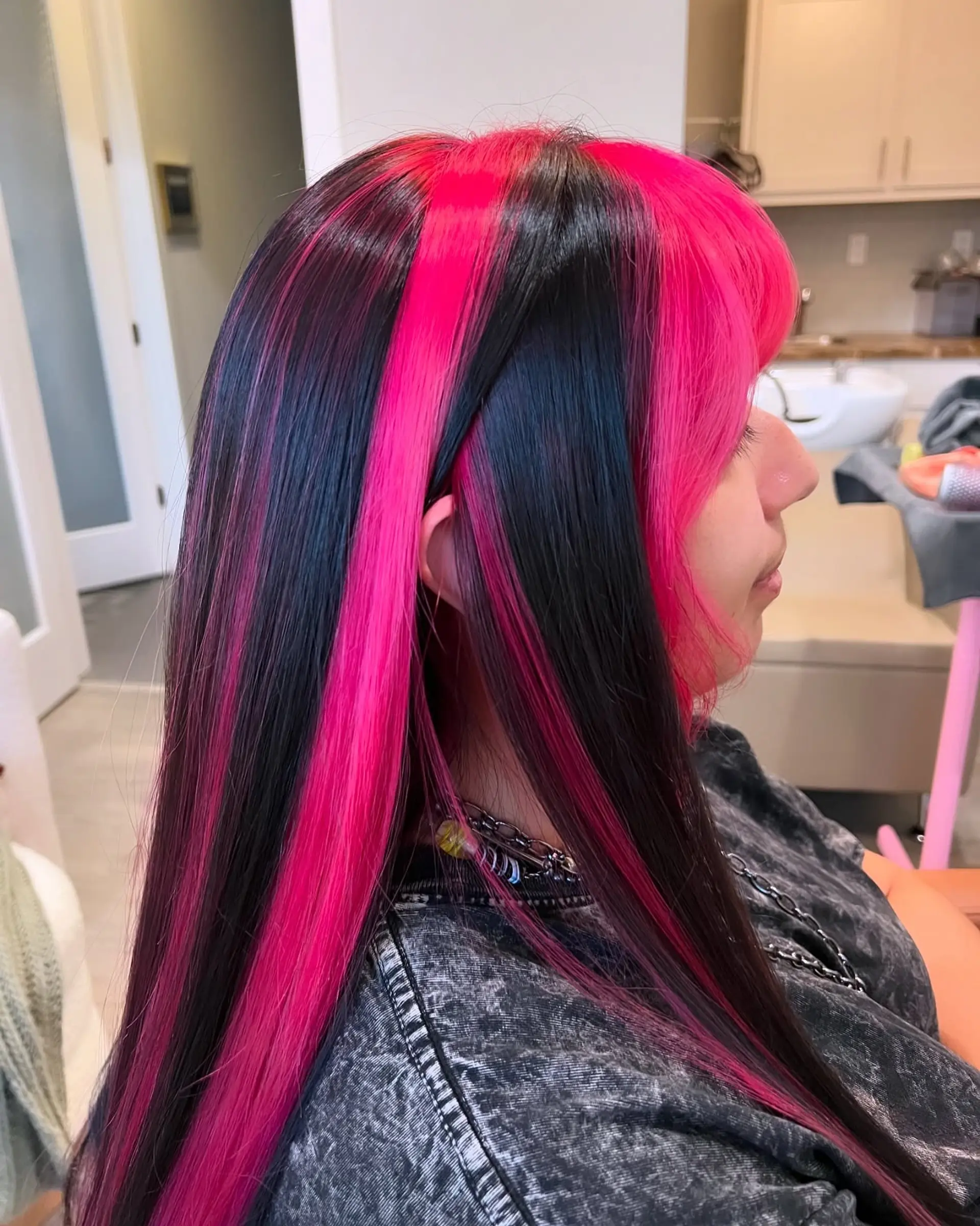 A bold, two-toned style featuring very long, straight hair with hot pink and black sections, complete with full, blunt bangs and face-framing layers. 5