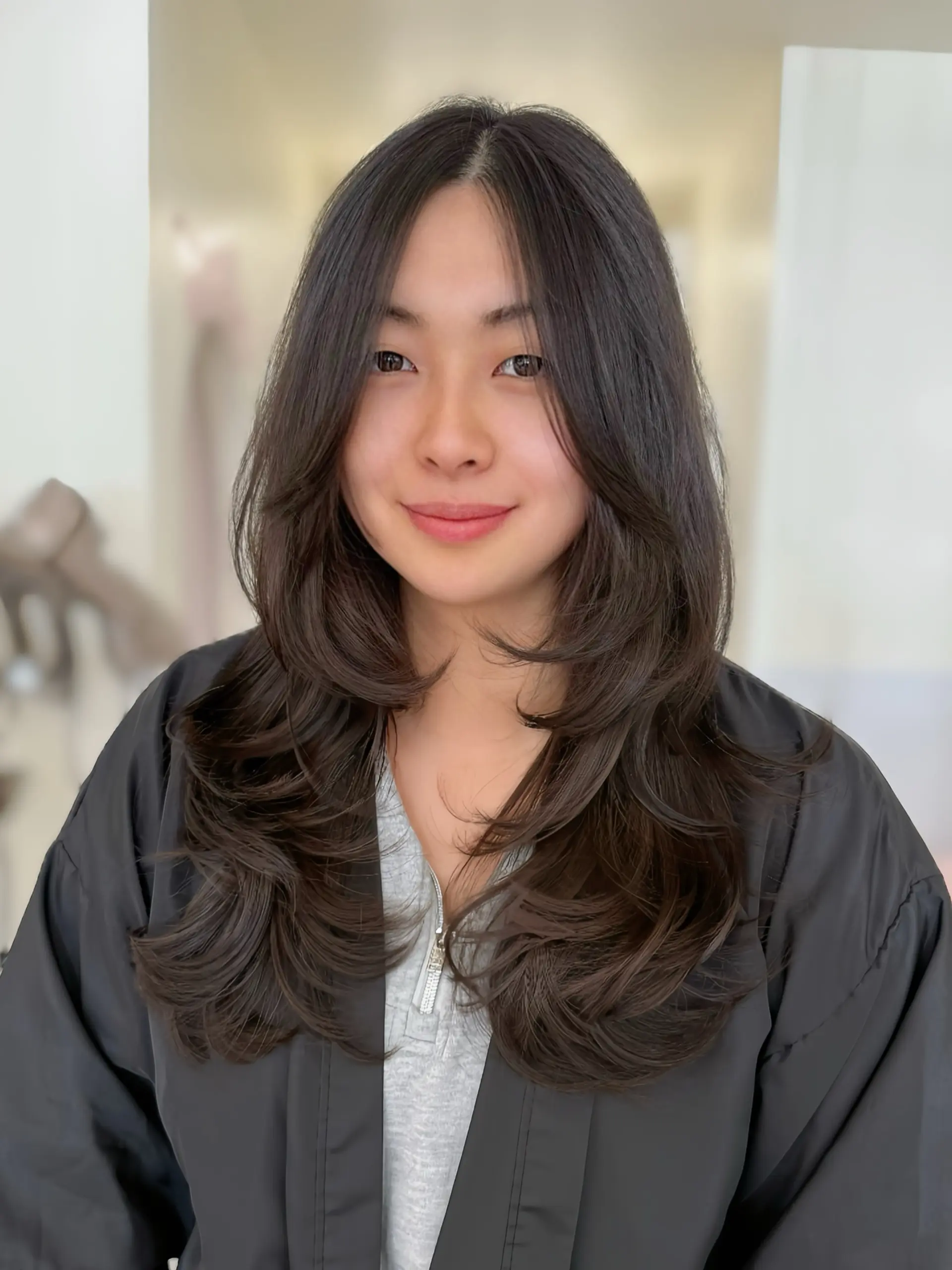 Long layered haircut featuring soft face-framing layers and inward-curled ends. 1