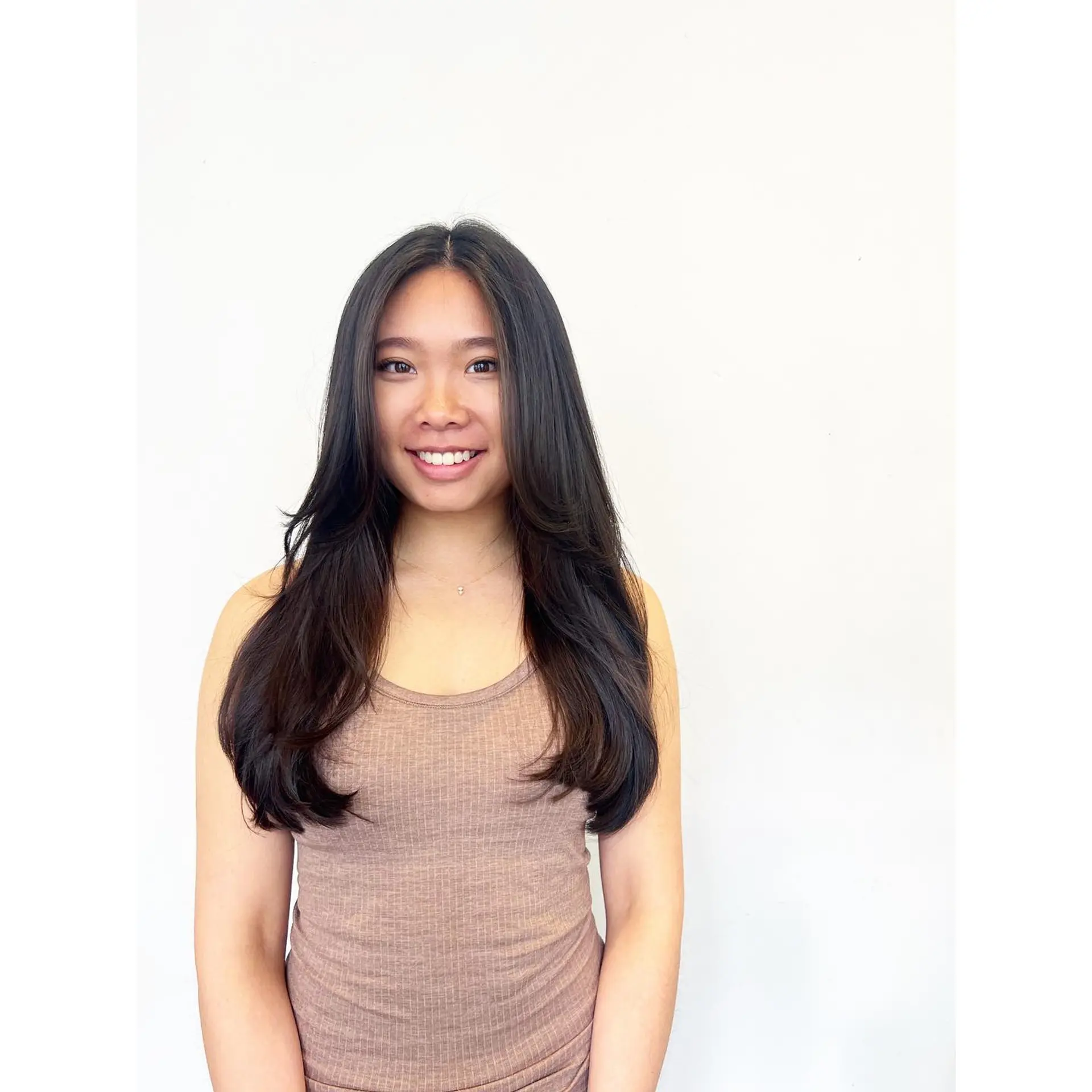 Long dark layered haircut featuring center-parted, face-framing layers and soft, curled-under ends. 1