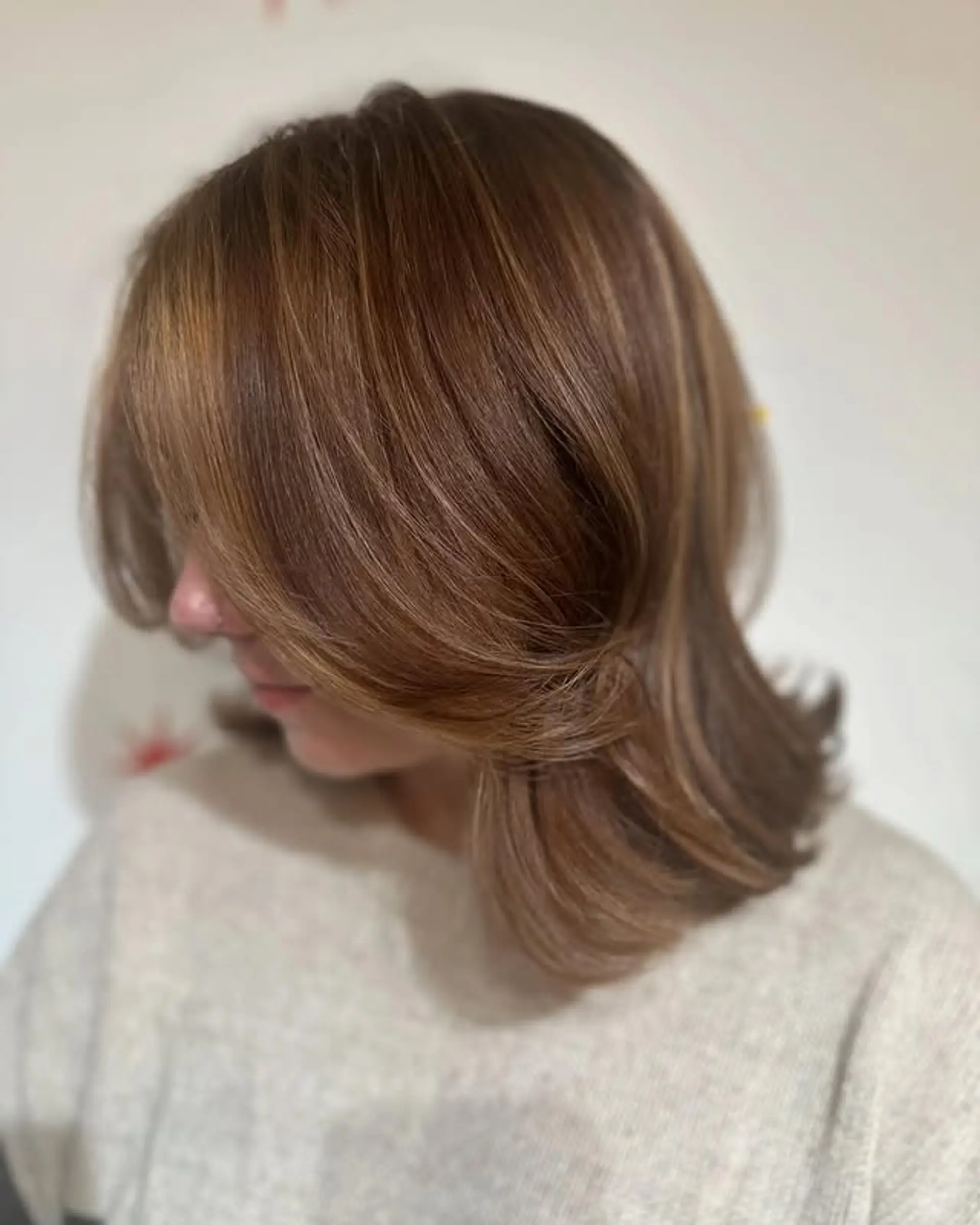 A medium-length butterfly cut with face-framing layers and caramel highlights. 1