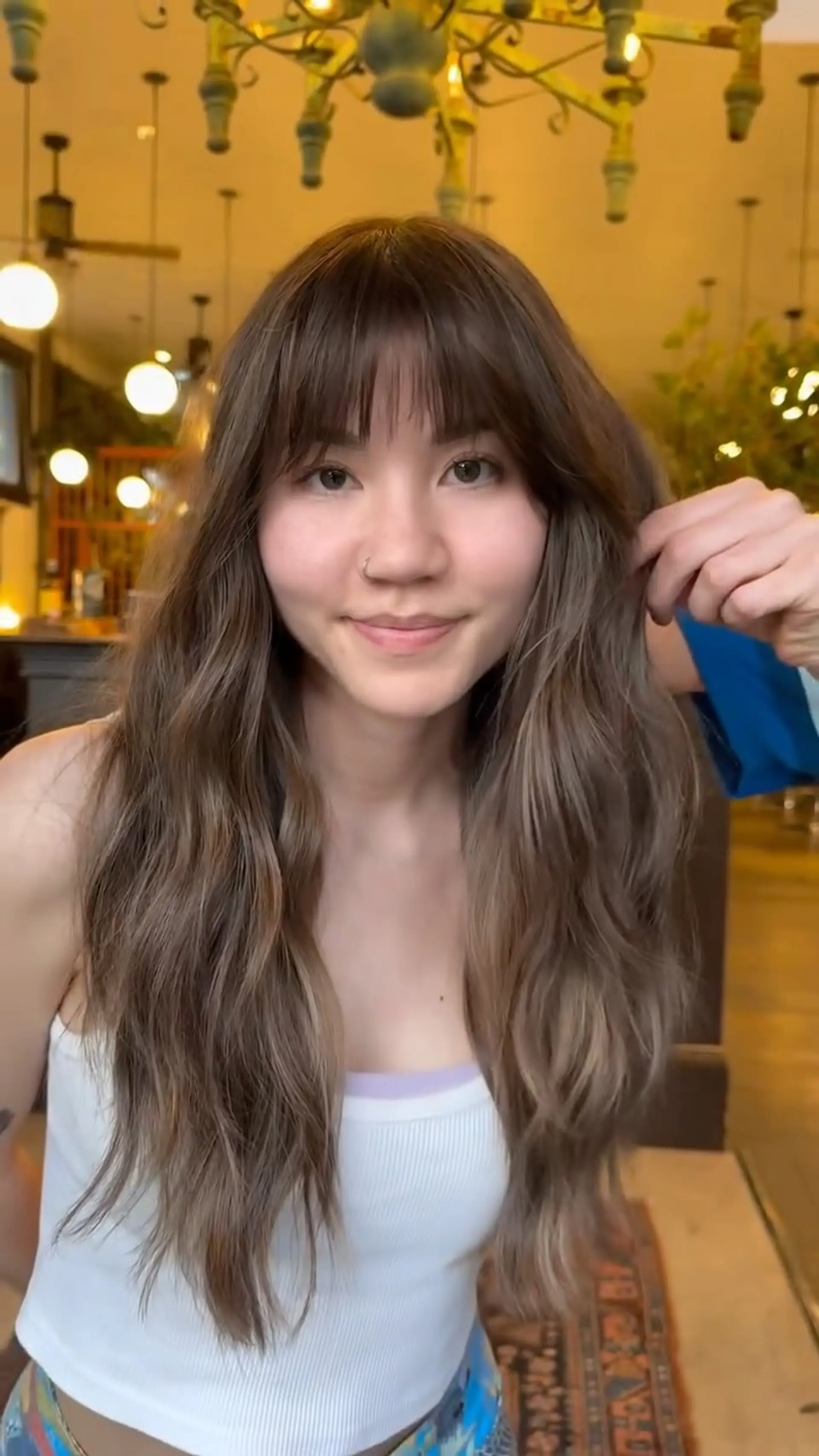 Long layered ash brown hair styled into soft, natural waves with wispy brow-skimming fringe. 1
