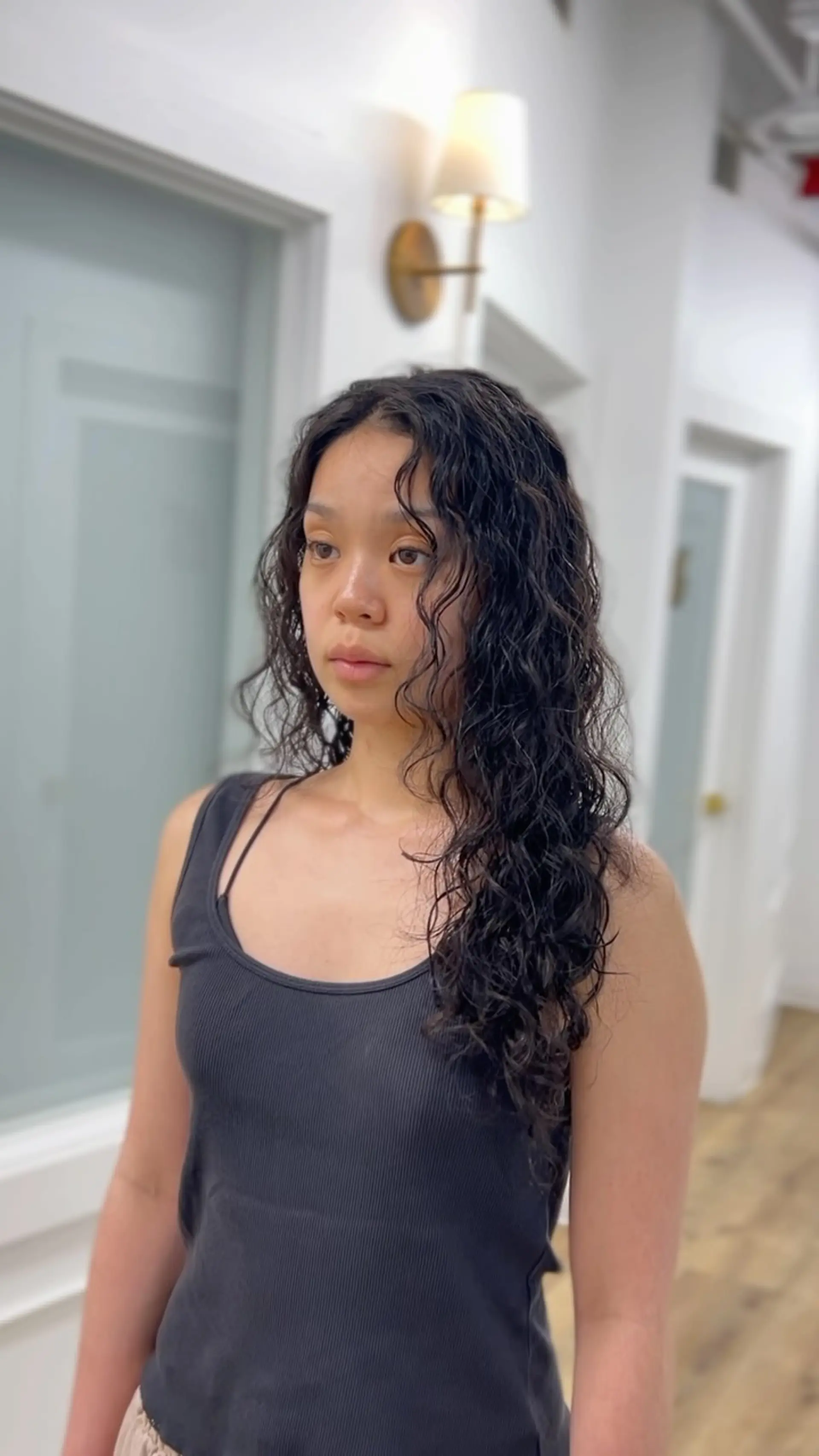 Long dark hair styled with defined, textured cold wave perm curls and face-framing tendrils. 1