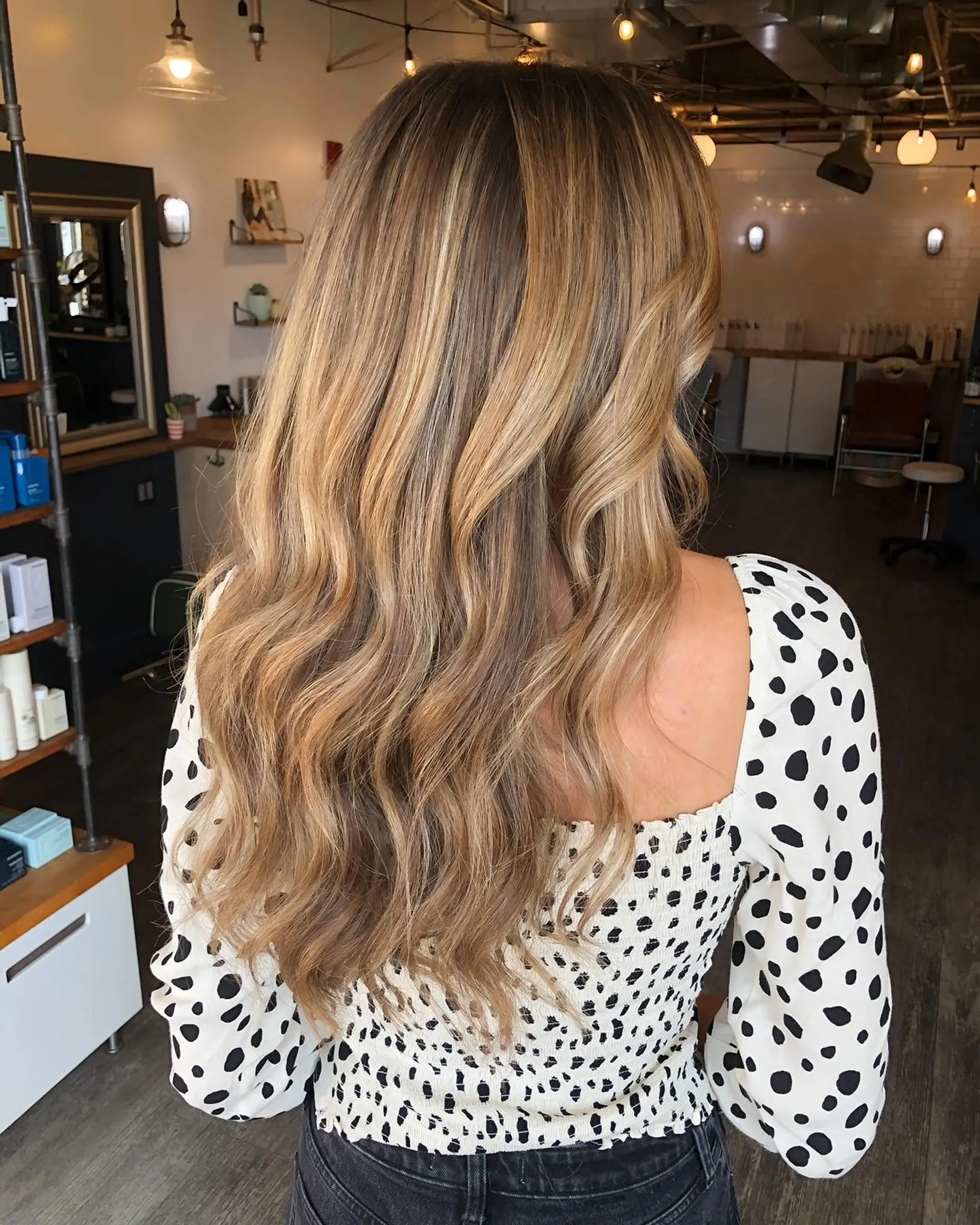 Long honey blonde balayage styled with relaxed, textured waves. 1