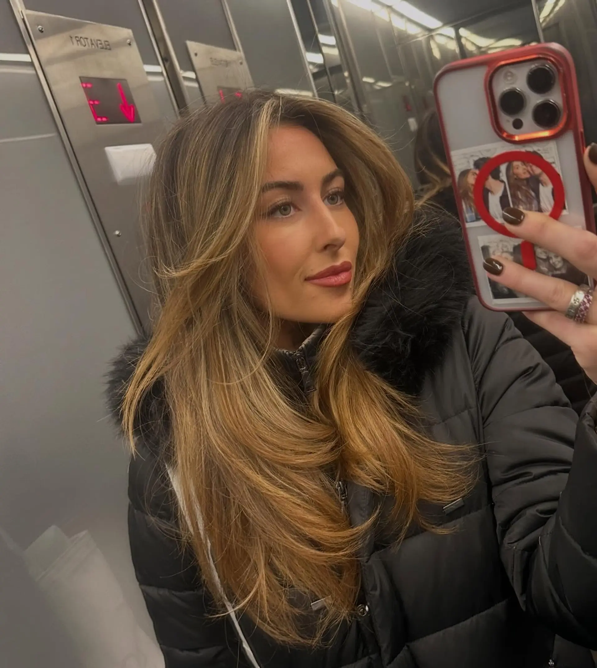 A voluminous long blowout featuring feathered face-framing layers and sun-kissed caramel highlights. 1