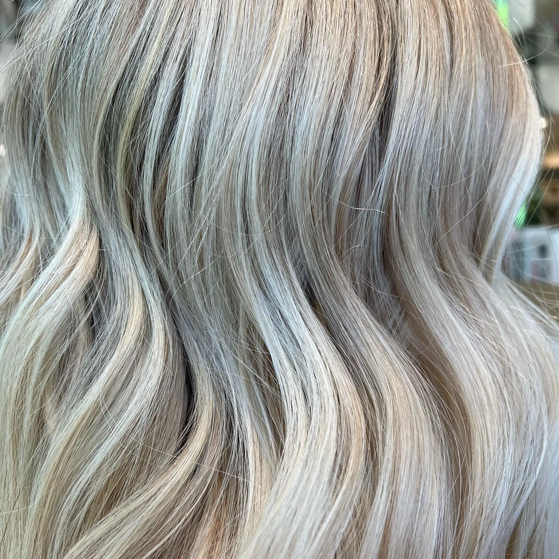 Close-up of radiant, cool-toned platinum blonde hair styled in soft dimensional waves. 1