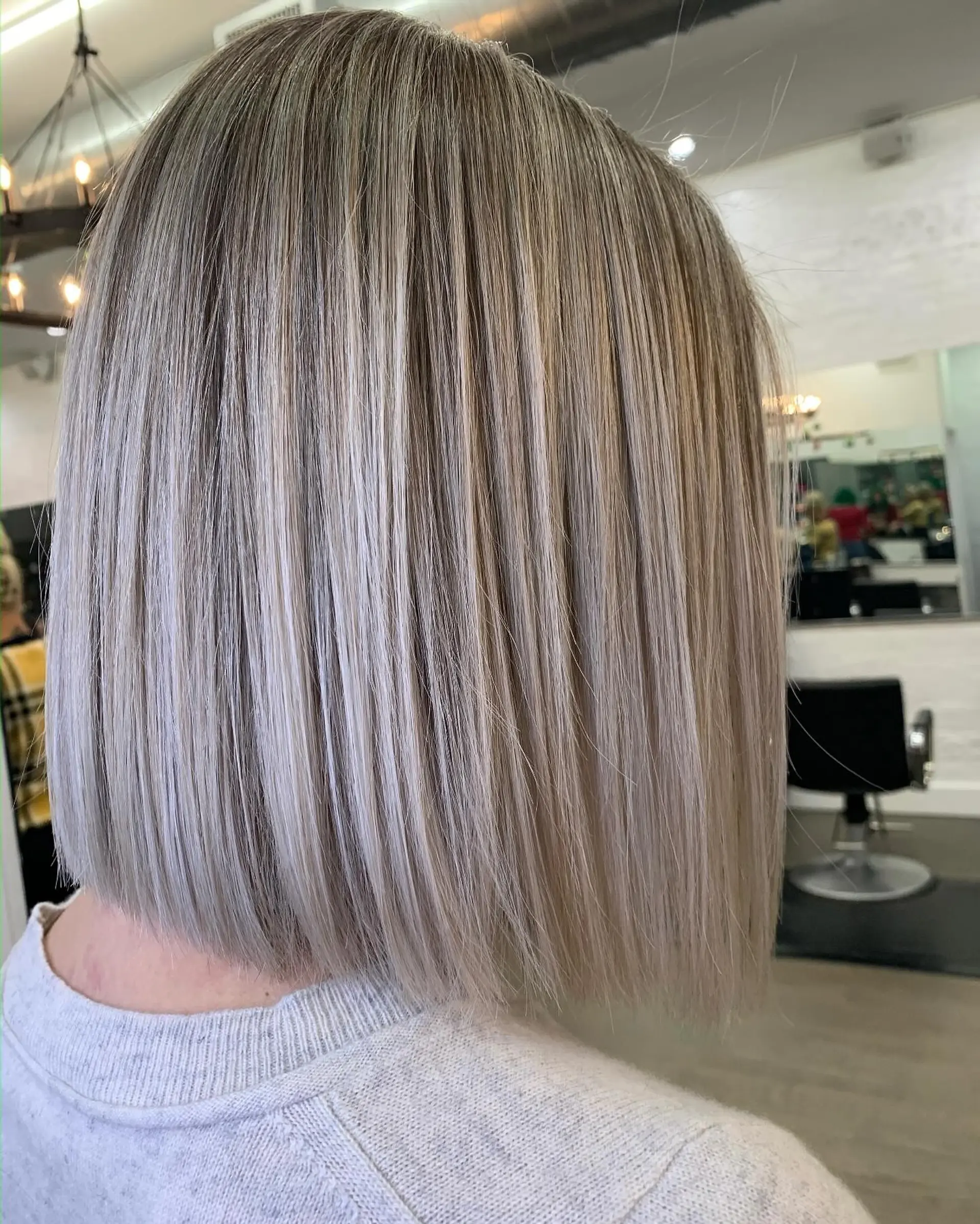 A sleek, blunt-cut bob featuring fine, cool ash blonde highlights with soft natural depth. 1