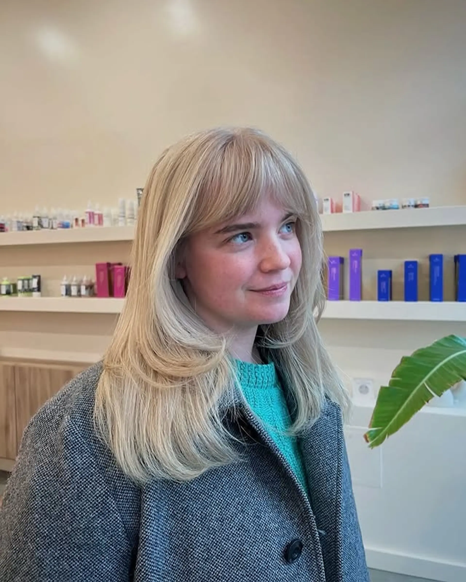 A medium-length layered haircut with full, straight bangs. 1