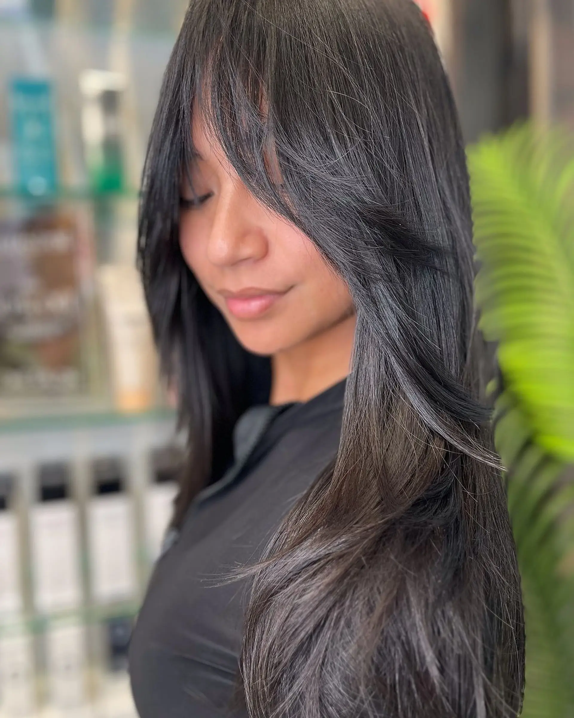 Long, silky black hair with sleek, straight locks and curtain bangs that part down the center. The layers add dimension and movement, while the bangs frame the face elegantly. 2