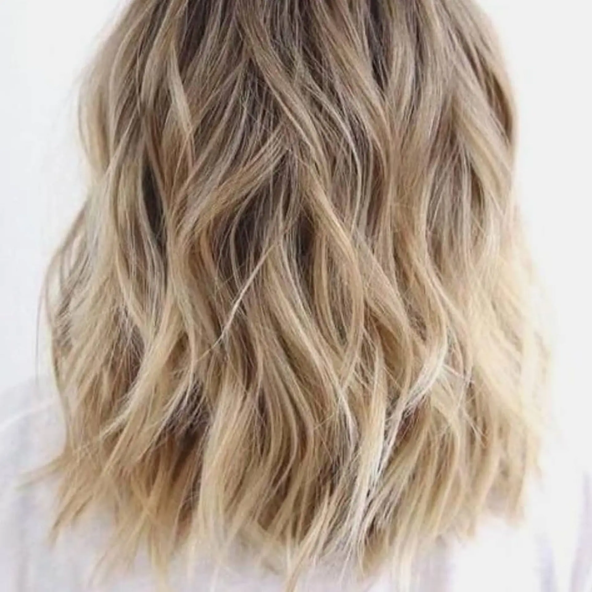 Shoulder-length textured lob styled in loose, tousled waves with cool dimensional blonde highlights. 1