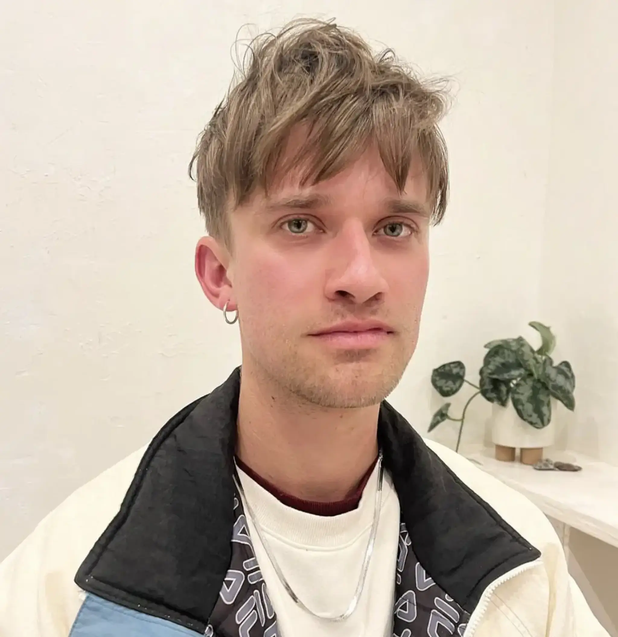 A medium length, light brown hairstyle with textured layers and a tousled fringe, embodying a relaxed and slightly messy look.