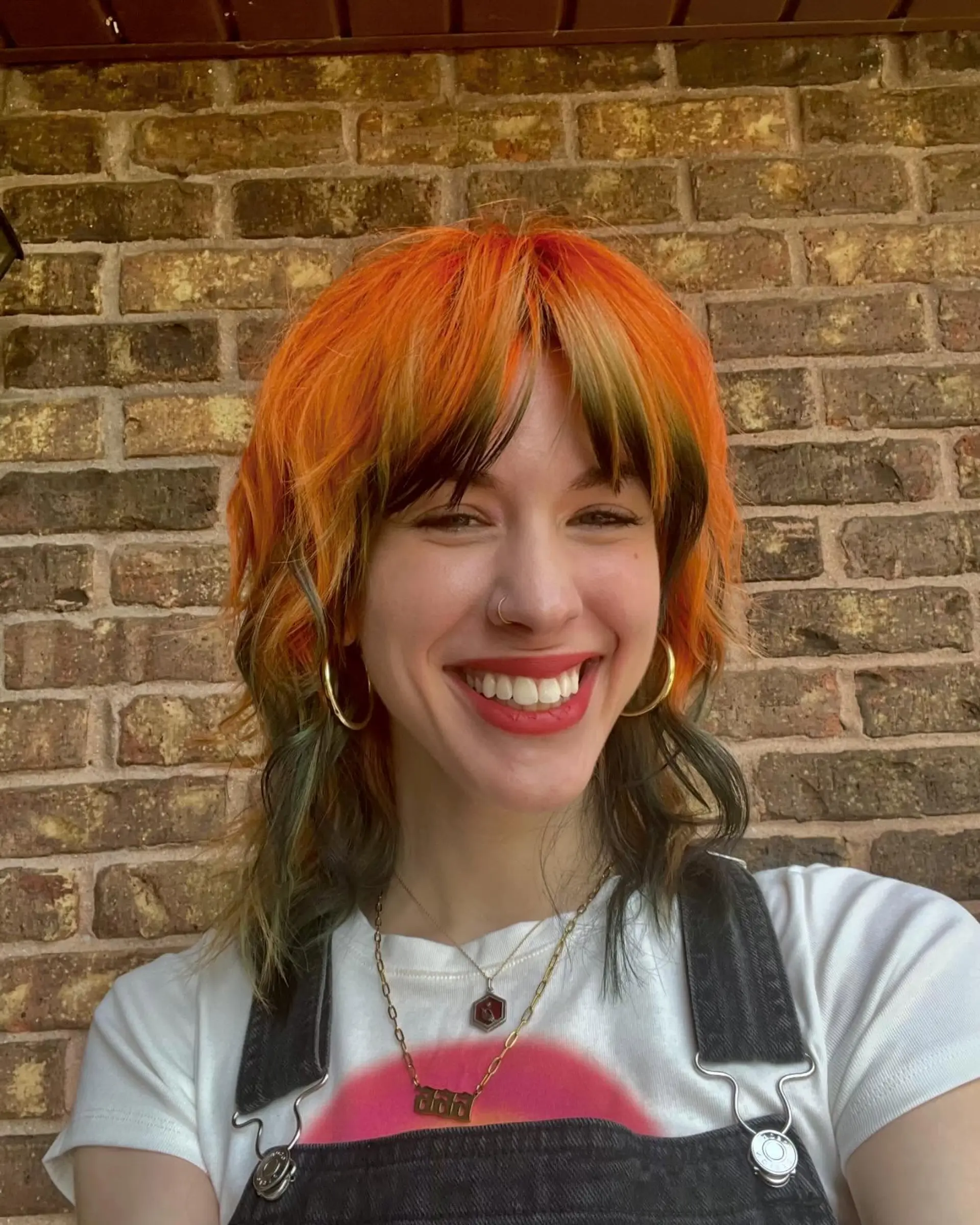 A vibrant textured shag mullet featuring bright electric orange hair with contrasting deep green bangs and underlayer. 1