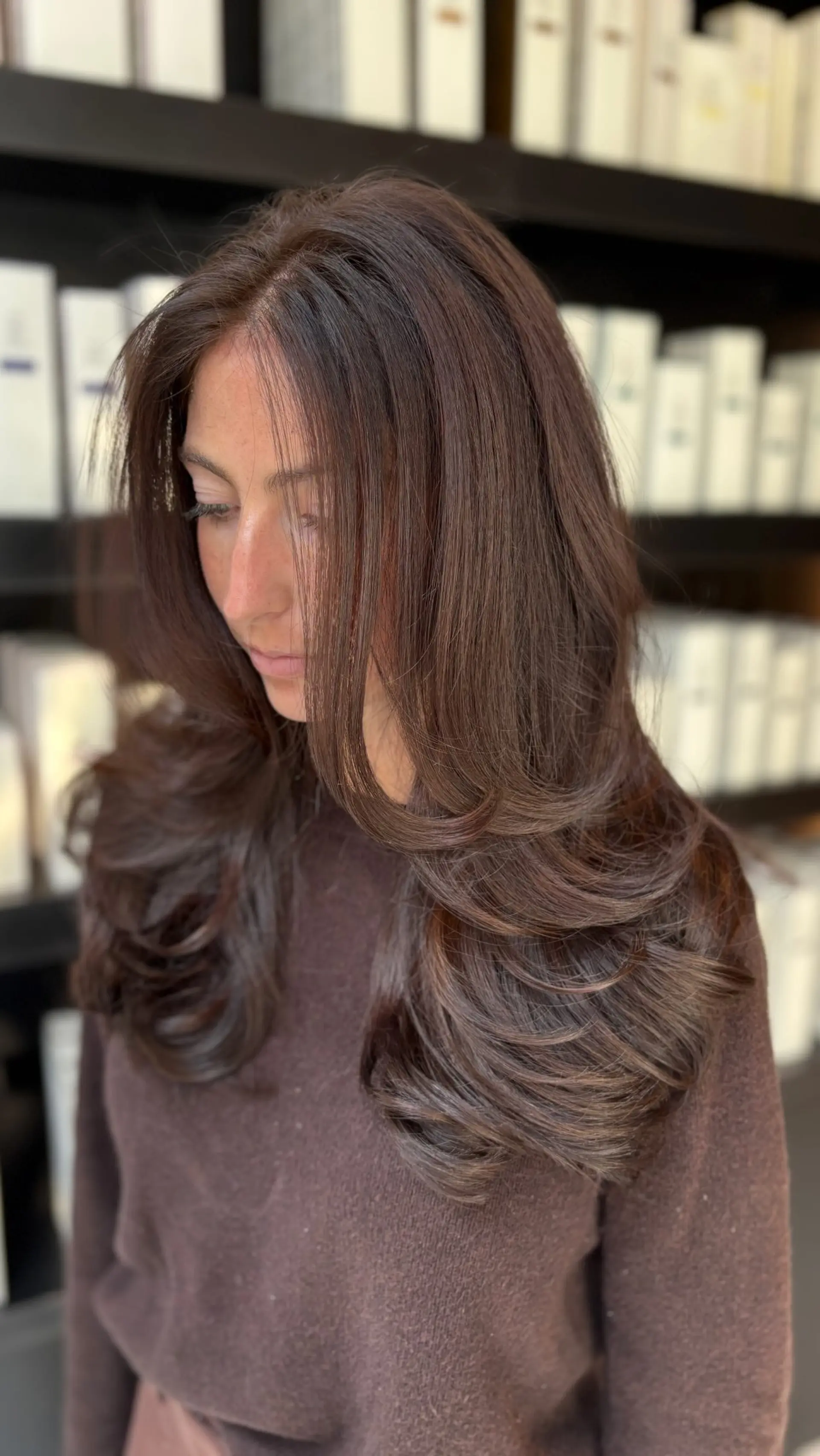 Long chocolate brown hair featuring soft face-framing layers and styled into a voluminous blowout with flipped-in ends. 1