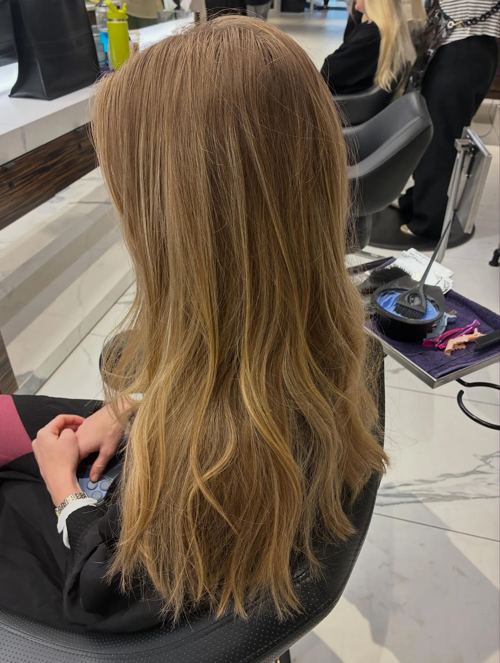 Long dimensional warm blonde hair styled in soft, cascading waves with seamless blended highlights. 1