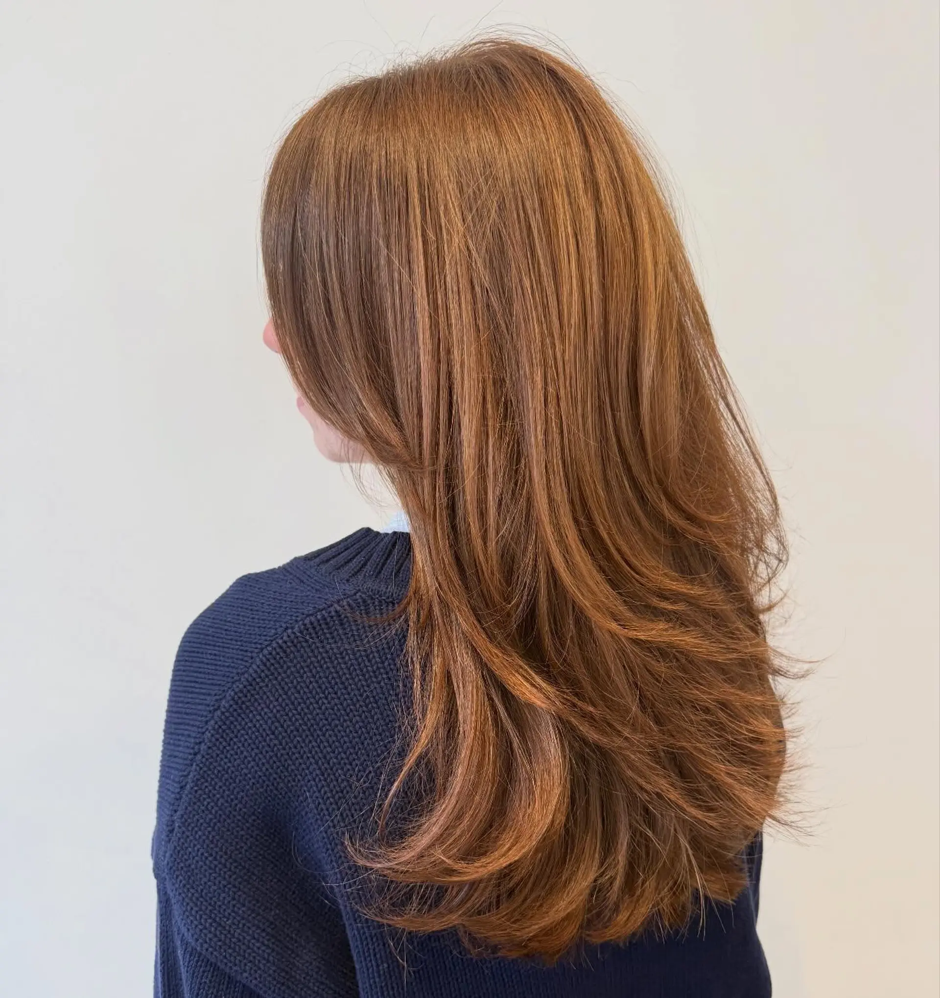 Long warm auburn hair featuring cascading face-framing layers with slightly curved ends. 1