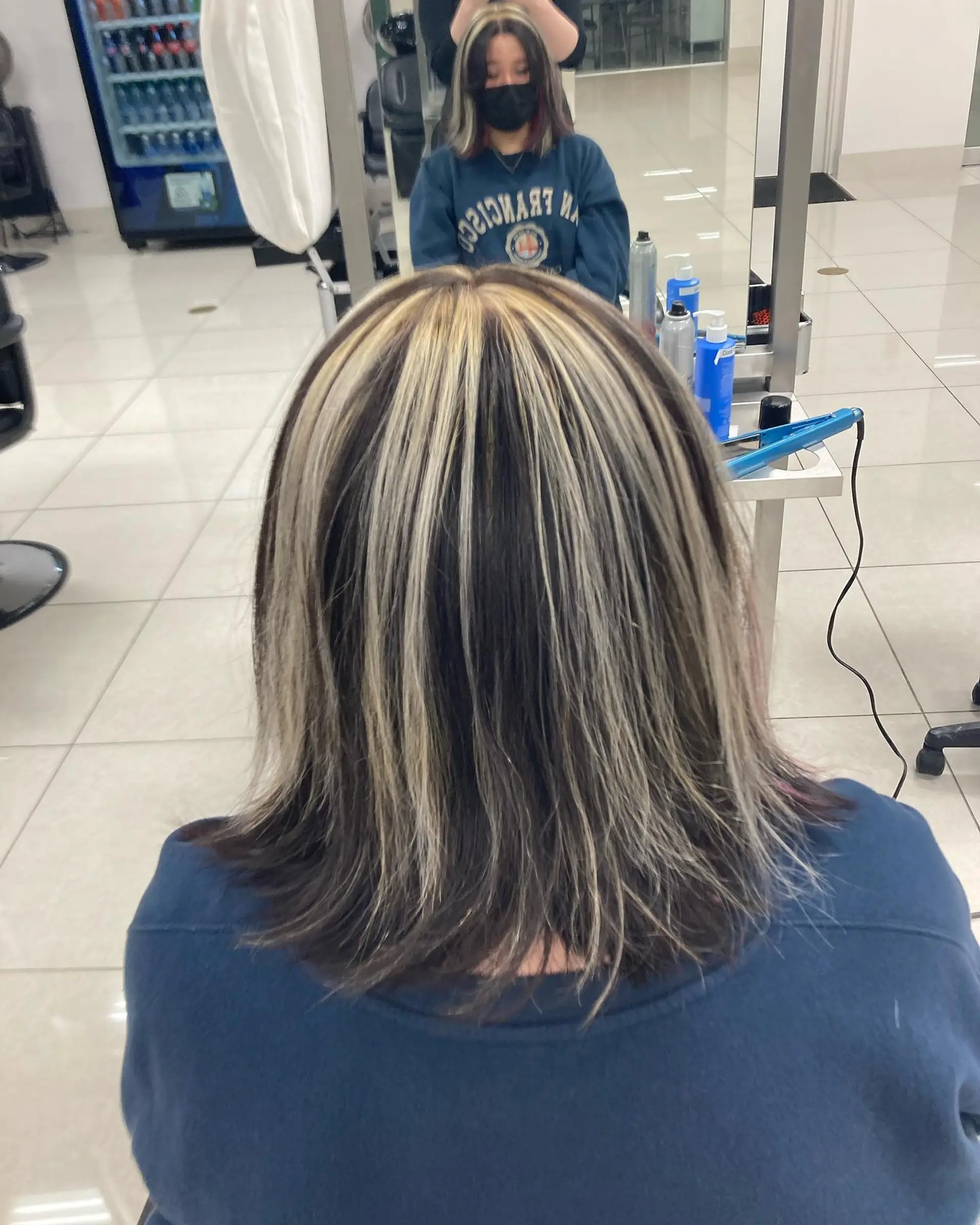 Medium-length straight dark hair styled with bold, high-contrast chunky blonde highlights. 1
