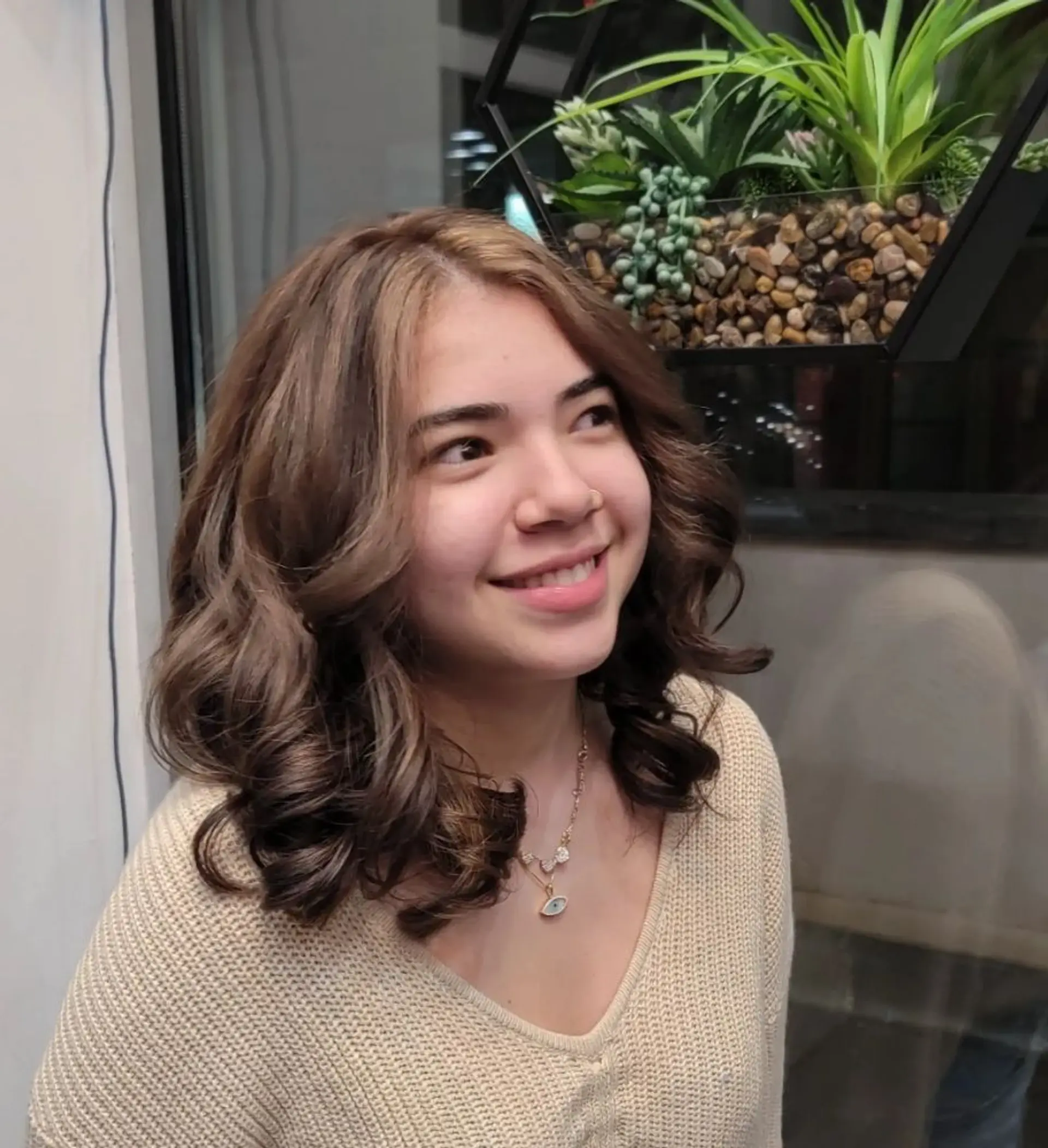Medium-length, wavy hair with chocolate brown base color and honey blonde highlights, styled with soft curls and a middle part, enhanced by a natural shine. 1