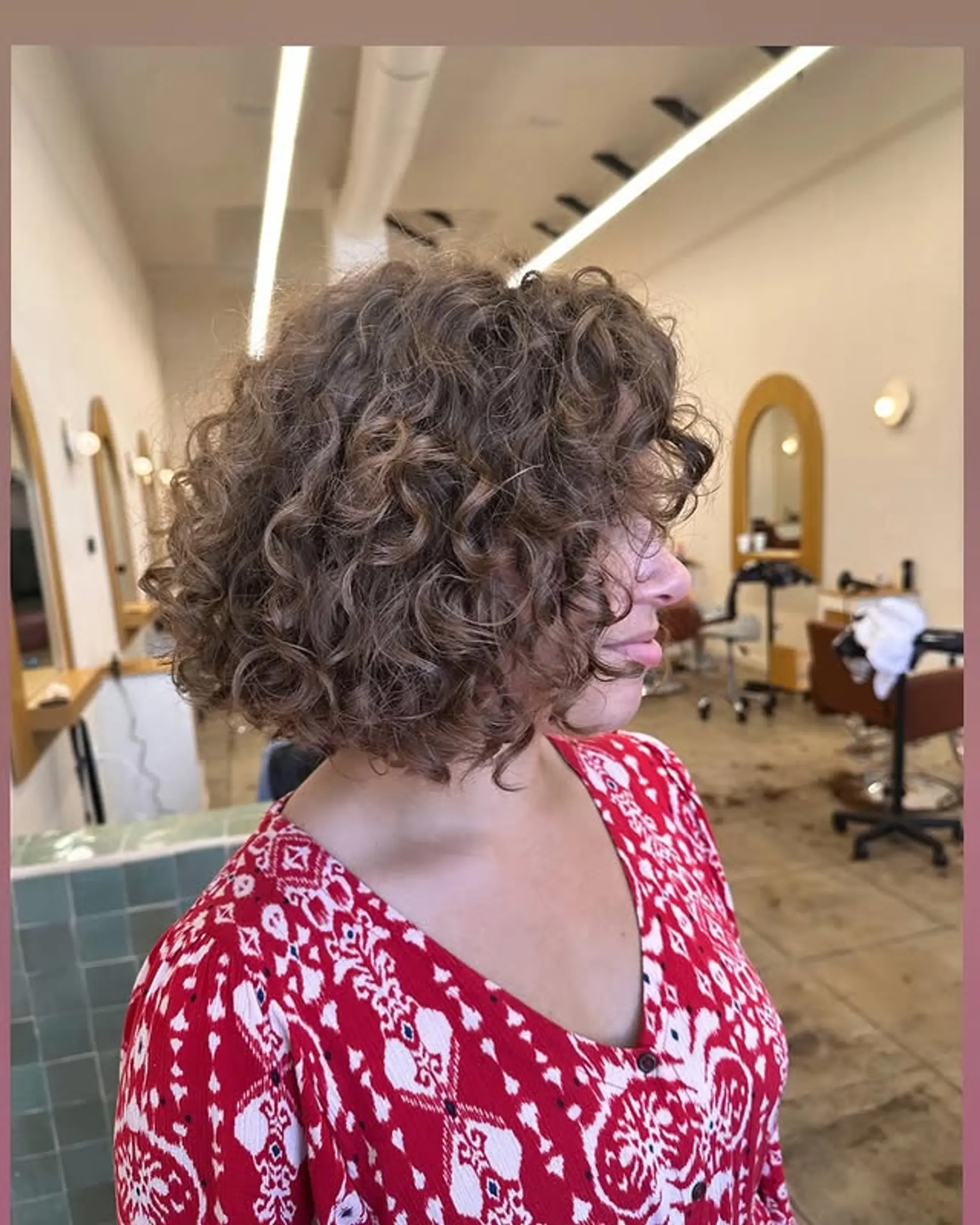 A curly bob haircut with natural, textured curls and face-framing bangs. 1