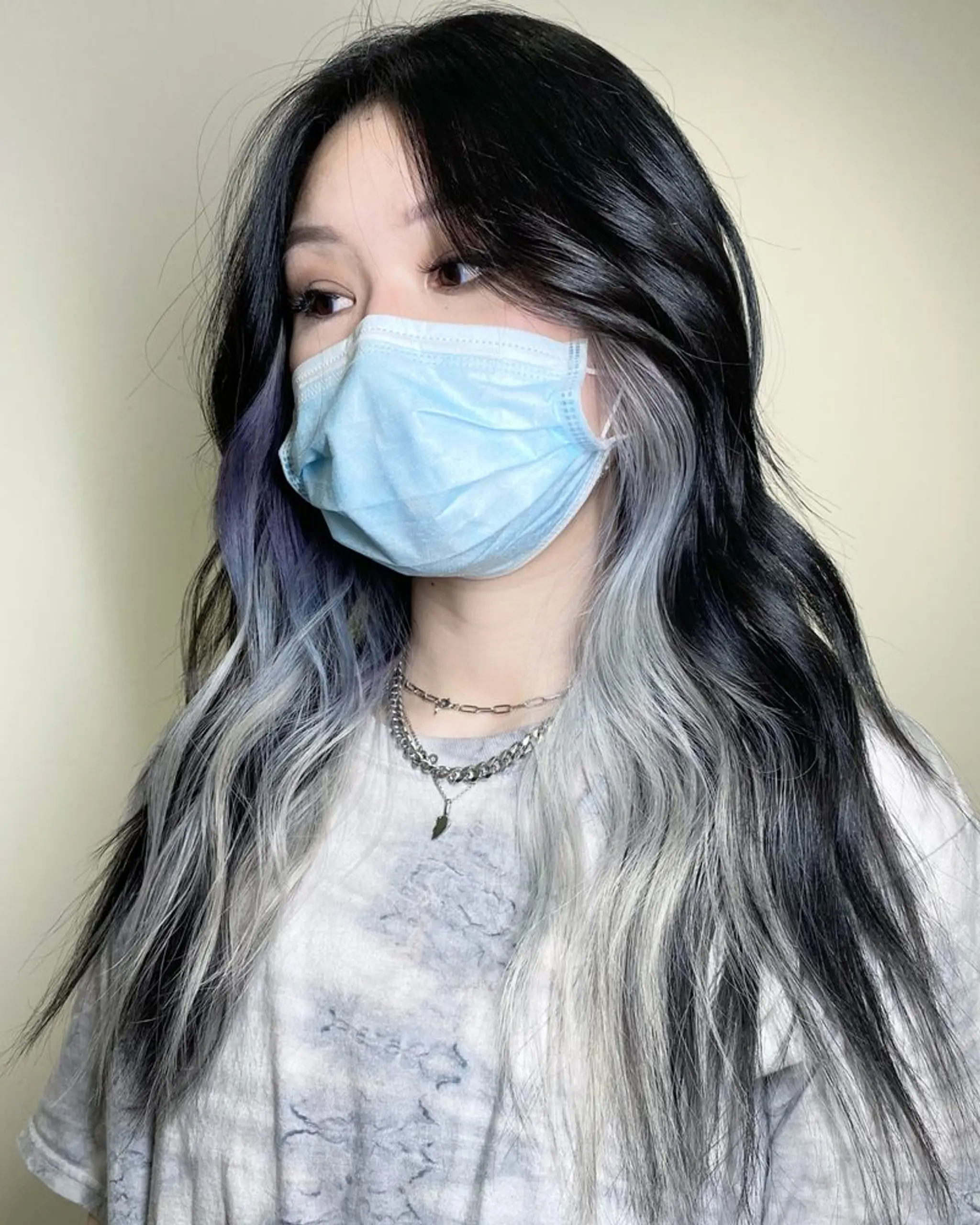 Long, wavy hair with a black to silver ombre effect, layered and styled in beach waves, featuring face-framing strands.