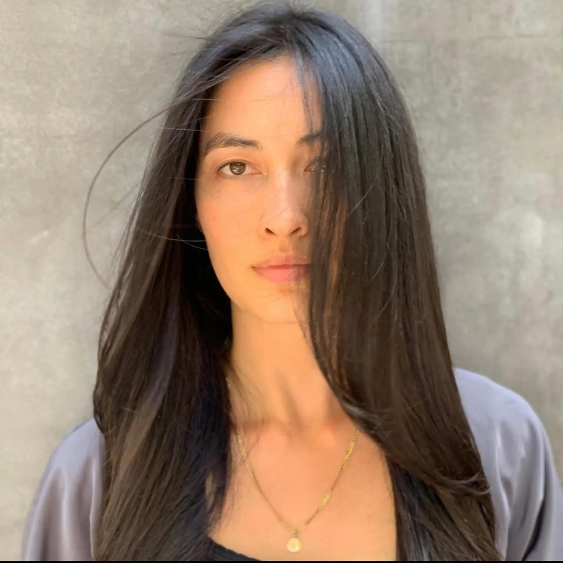 Long, sleek brunette hair styled straight with a center part and soft face-framing strands. 1