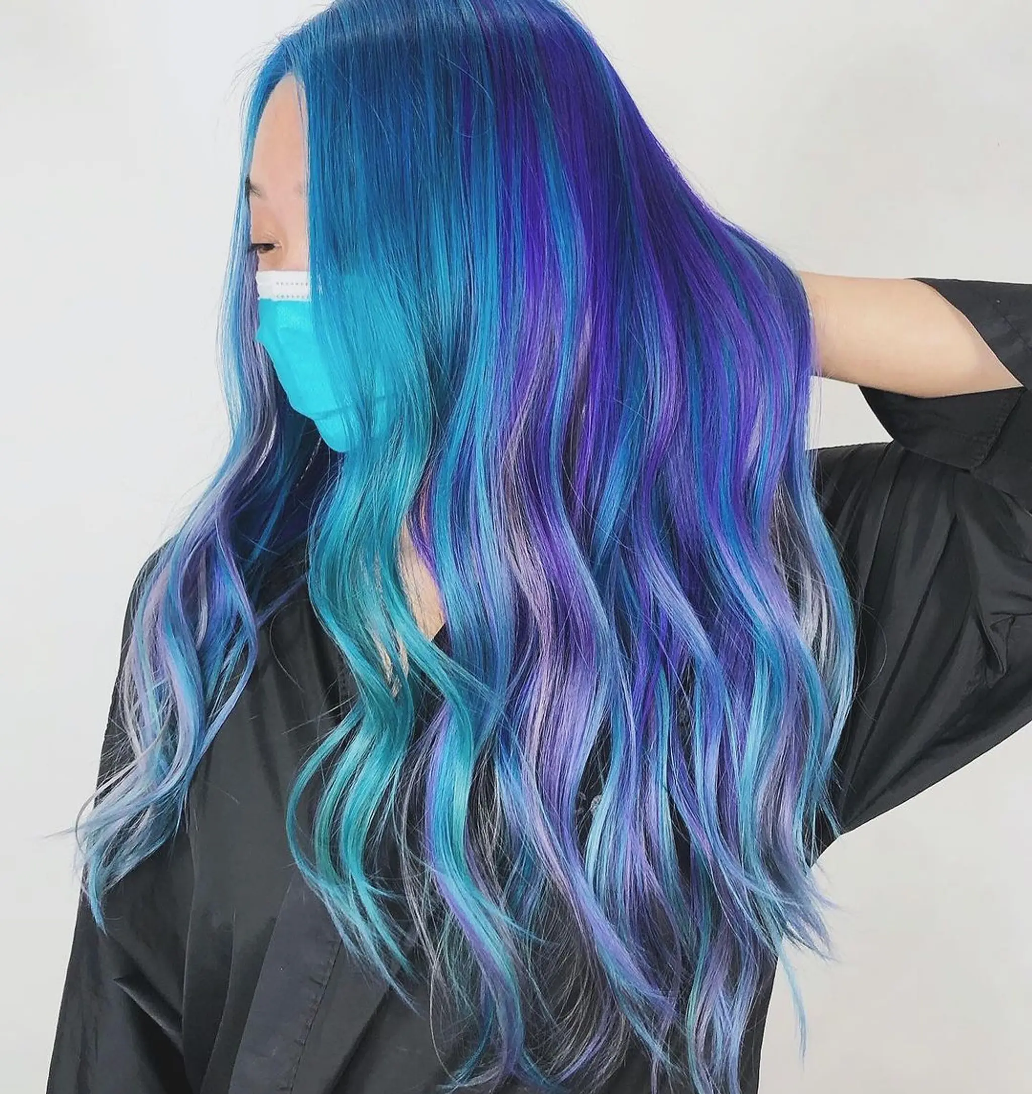 A very long, wavy hairstyle featuring vibrant blue, purple, and turquoise tones in a gradient effect, styled with loose waves.
Stylist - @xcellent_jason