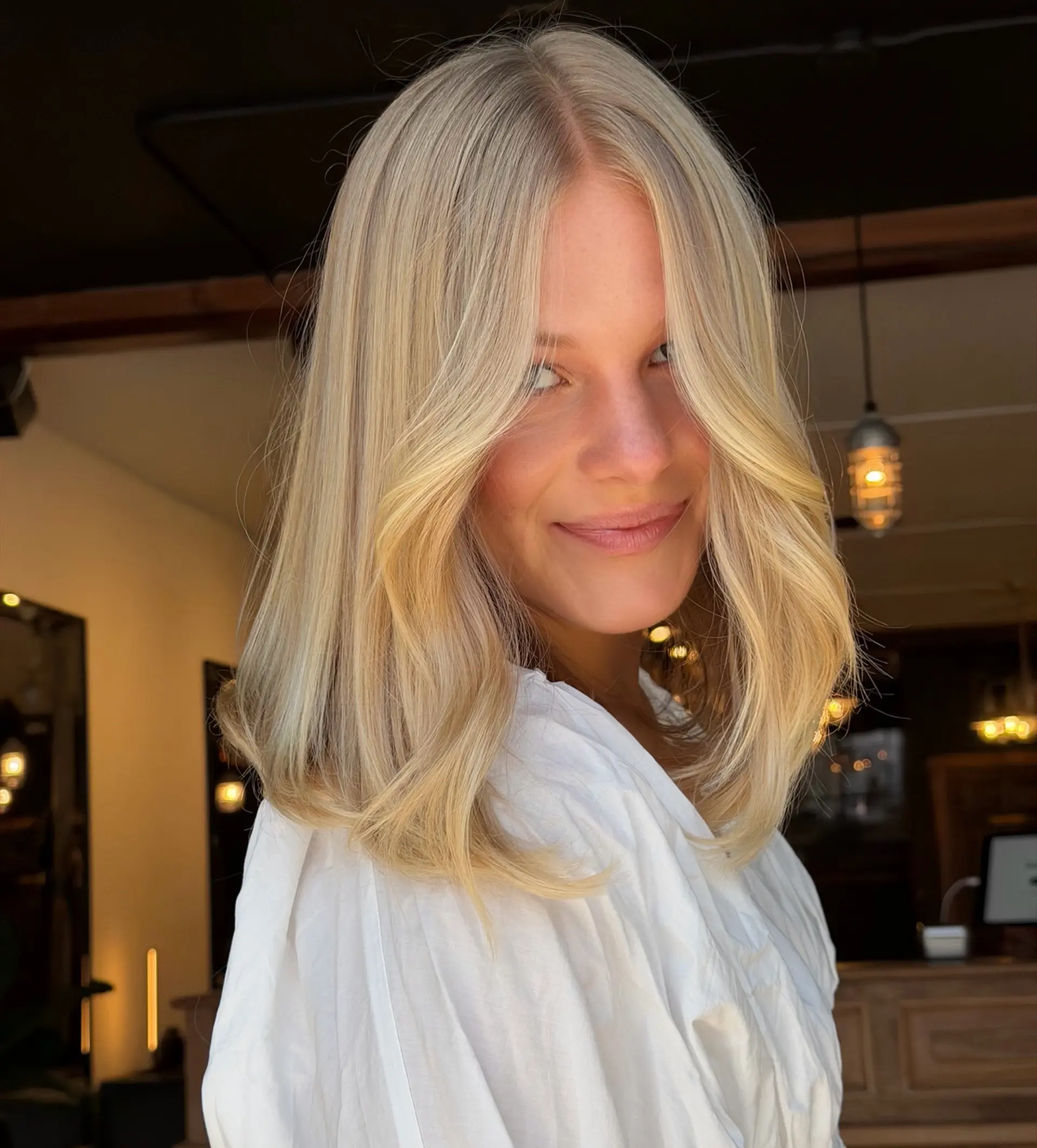 A collarbone-skimming blonde lob styled with soft inward curves and sweeping face-framing layers. 1