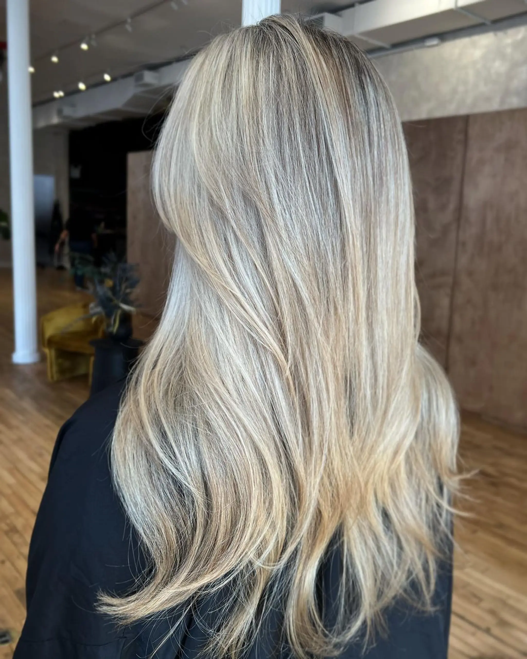 Long, wavy hair with a blend of blonde and golden highlight colors, featuring soft waves that cascade naturally down the back.