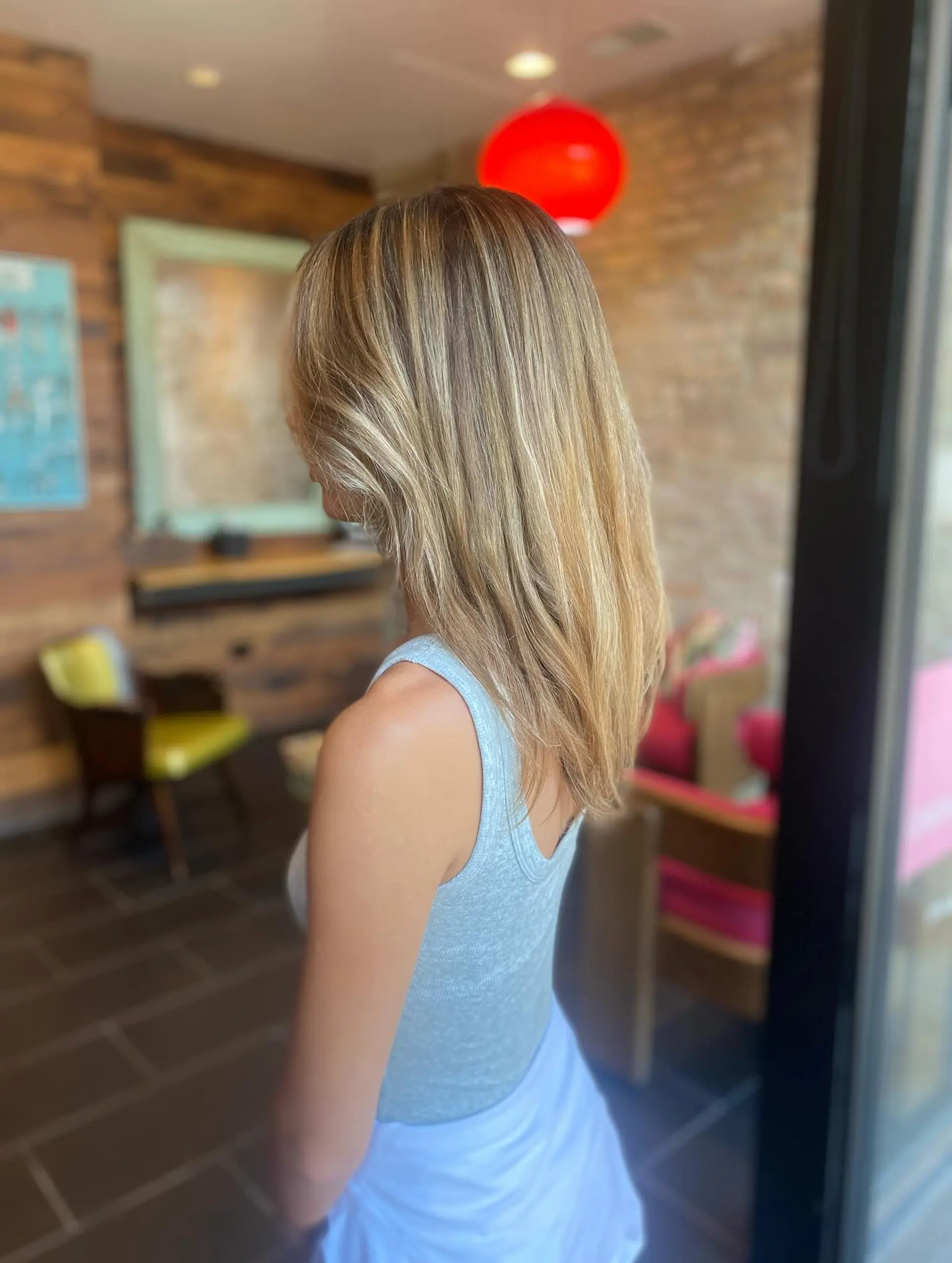 A medium-length cut with layers and face-framing pieces. Bronde color created with highlights to add dimension. 3