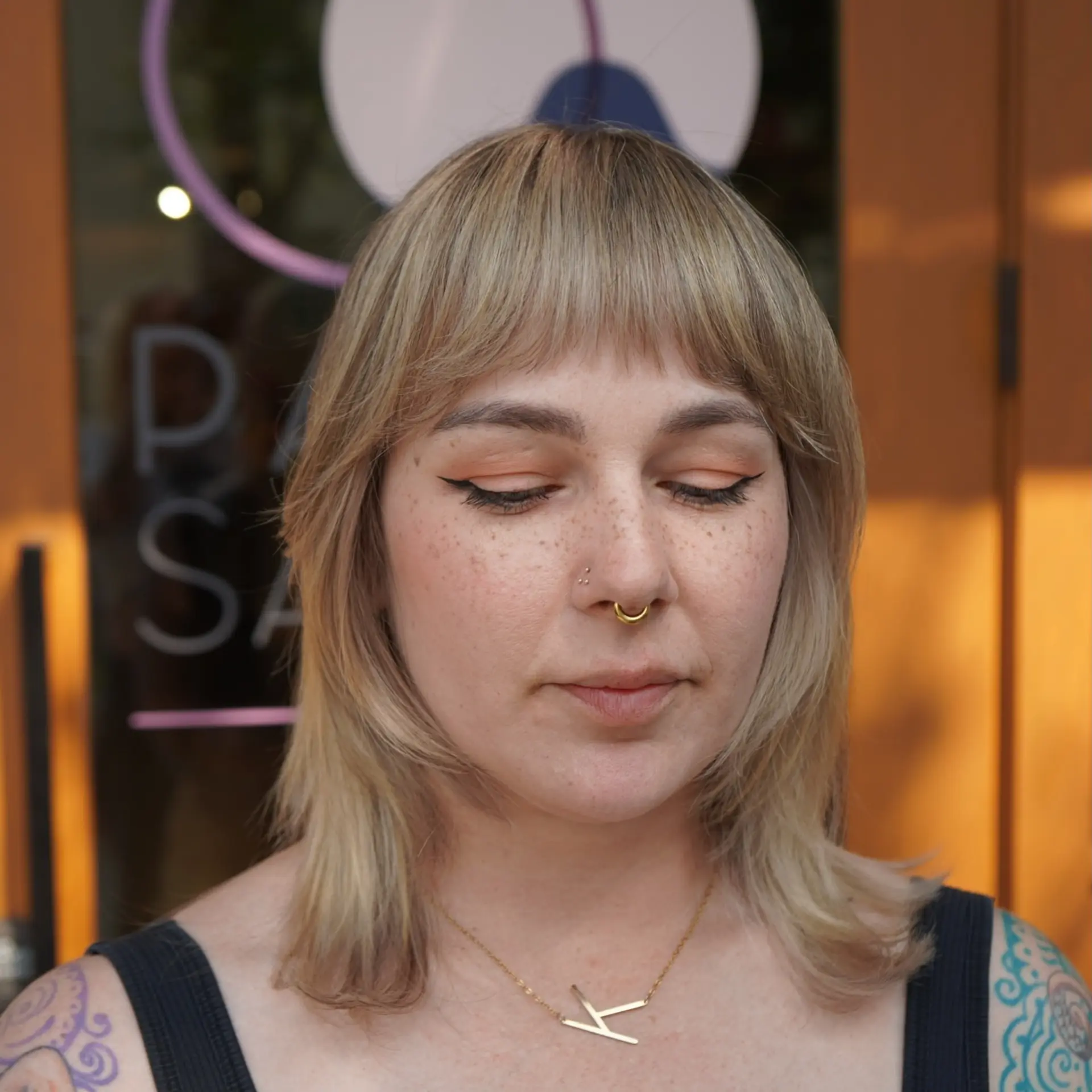 A textured modern shag haircut featuring light, feathery face-framing layers and soft, textured straight-across bangs that gently frame the eyes and cheekbones. 1