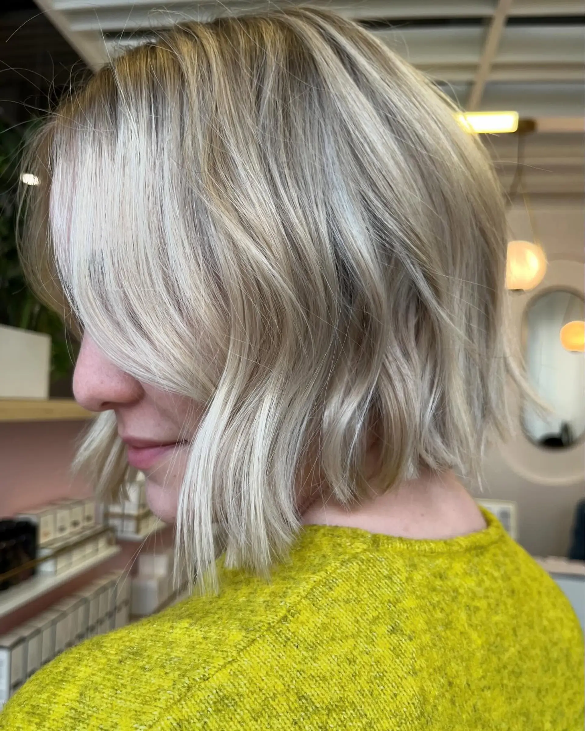 A chin-length blonde bob styled with subtle bends and textured ends, accompanied by soft swept bangs. 1