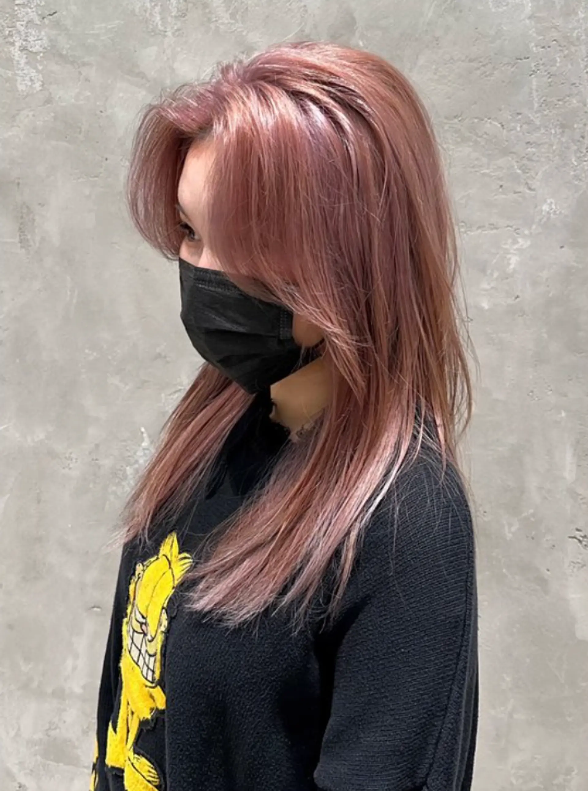 A long, straight hairstyle in a soft rose gold and blush pink hue, featuring a side part with gently layered and face-framing locks that present a sleek and polished appearance. 1