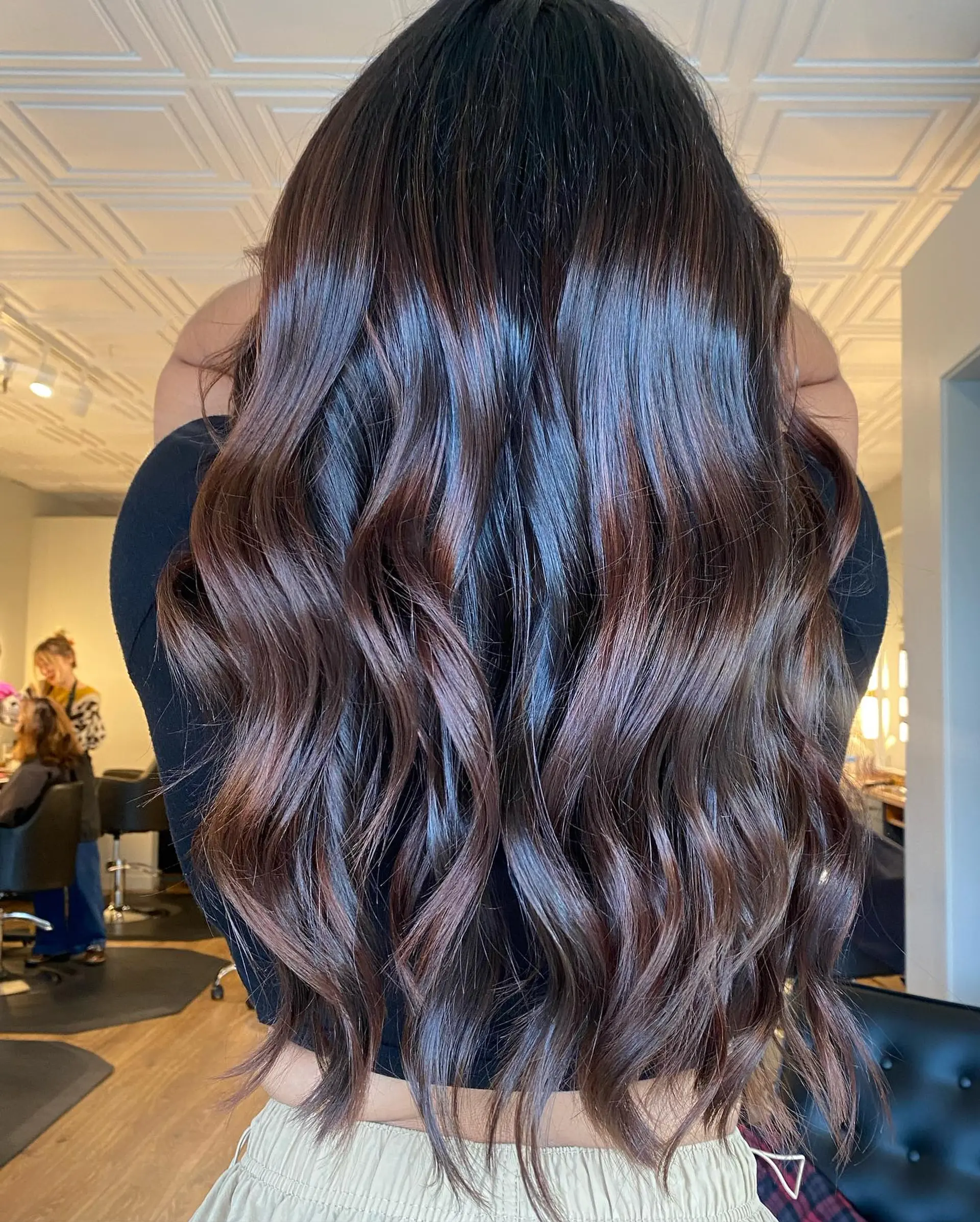 Long, glossy brunette hair with warm chocolate balayage accents styled into soft, flowing waves. 1