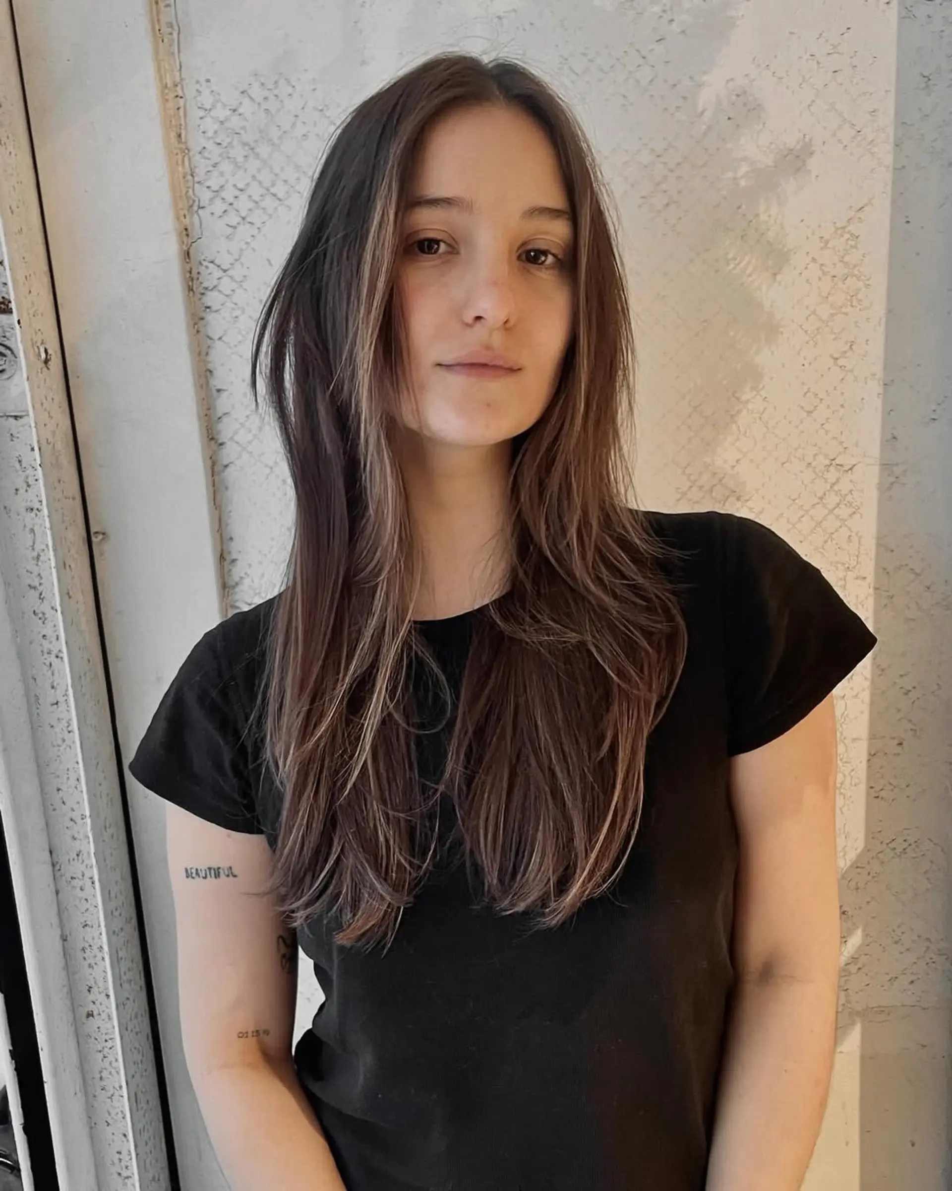 Long wavy dark brown hair, center-parted with natural waves and subtle volume, exuding a casual elegance. 2