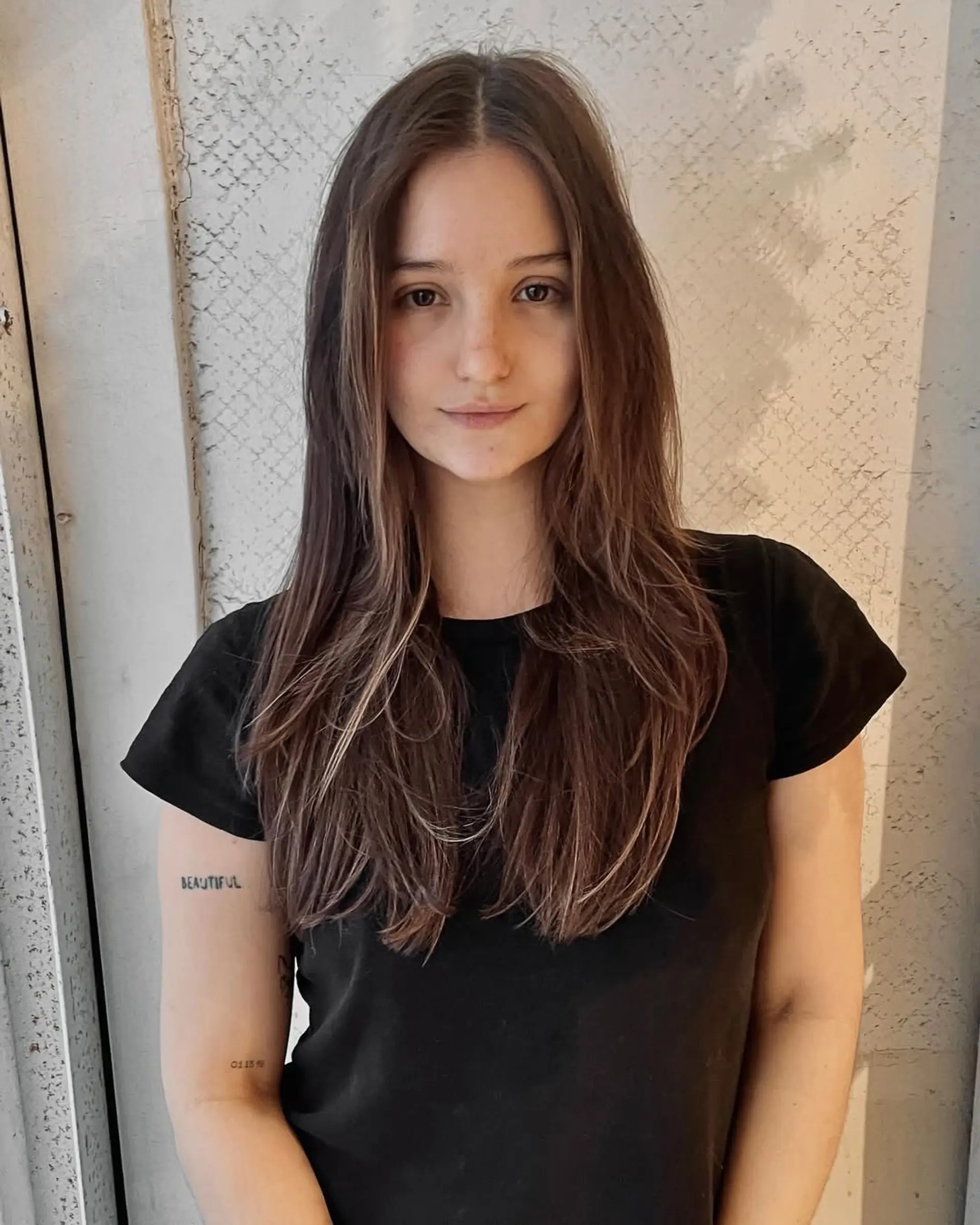 Long wavy dark brown hair, center-parted with natural waves and subtle volume, exuding a casual elegance. 1