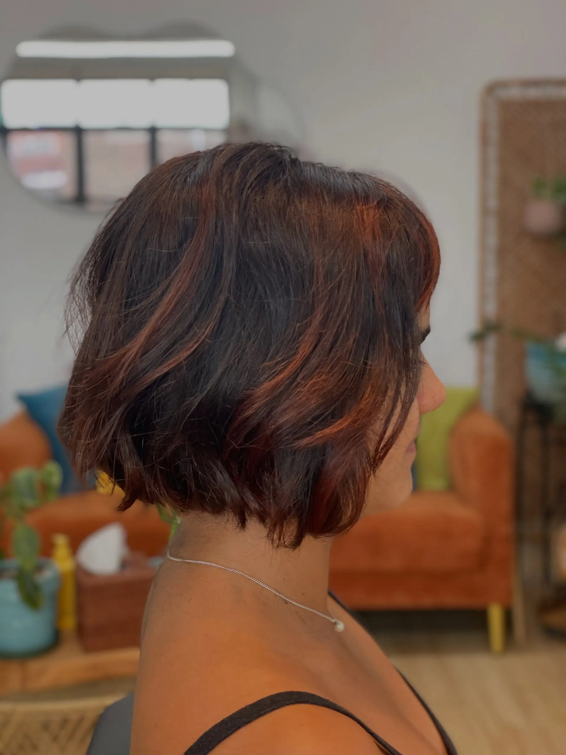 A chin-length textured bob with loose, tousled waves and warm auburn-copper highlights throughout a dark brown base. 1
