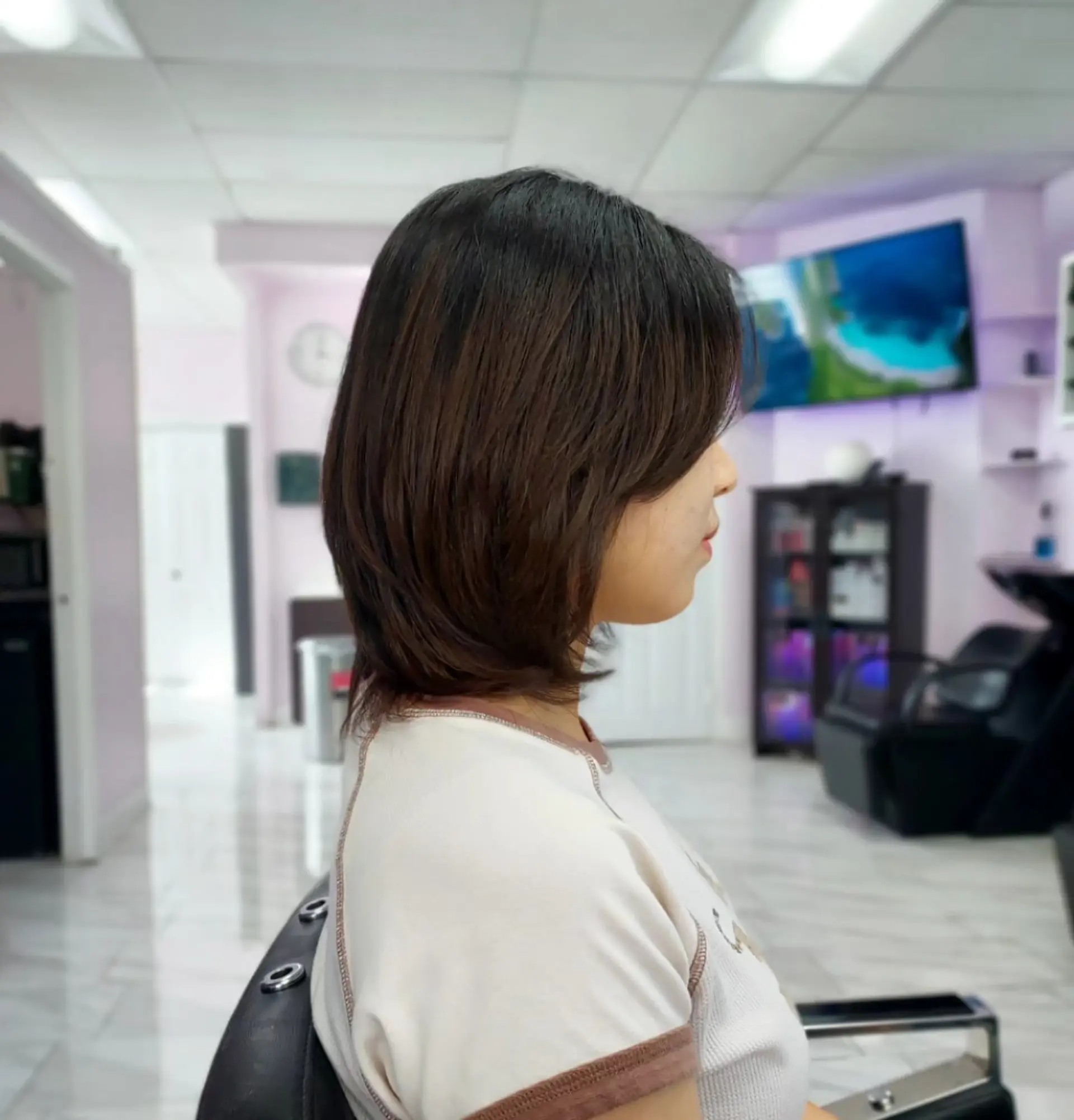 Side view of a soft layered short haircut with gently tapered ends in natural dark brown. 1