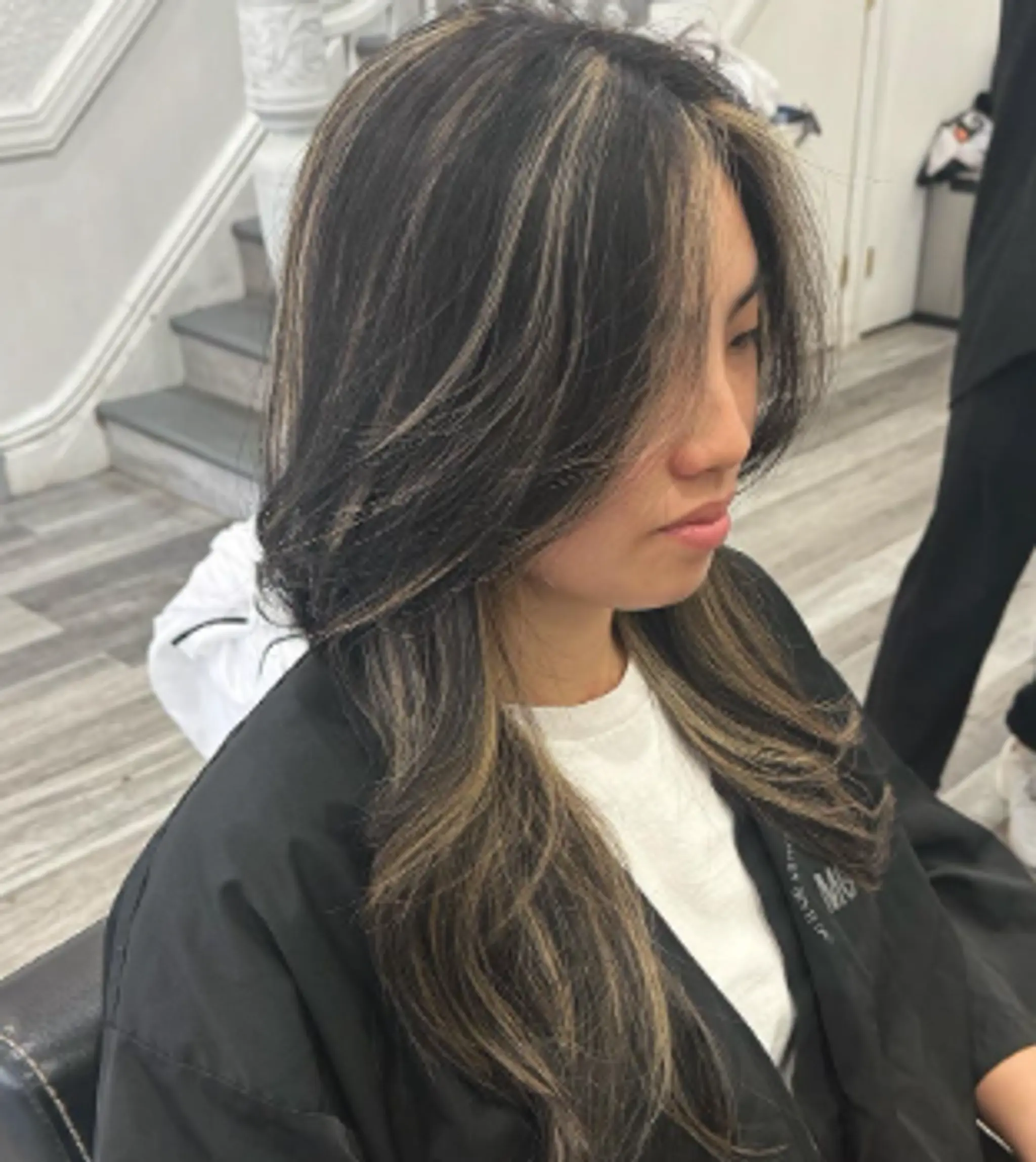 Medium-length, wavy hair with black and silver highlights. The cut includes layered, face-framing strands that add dimension and movement.