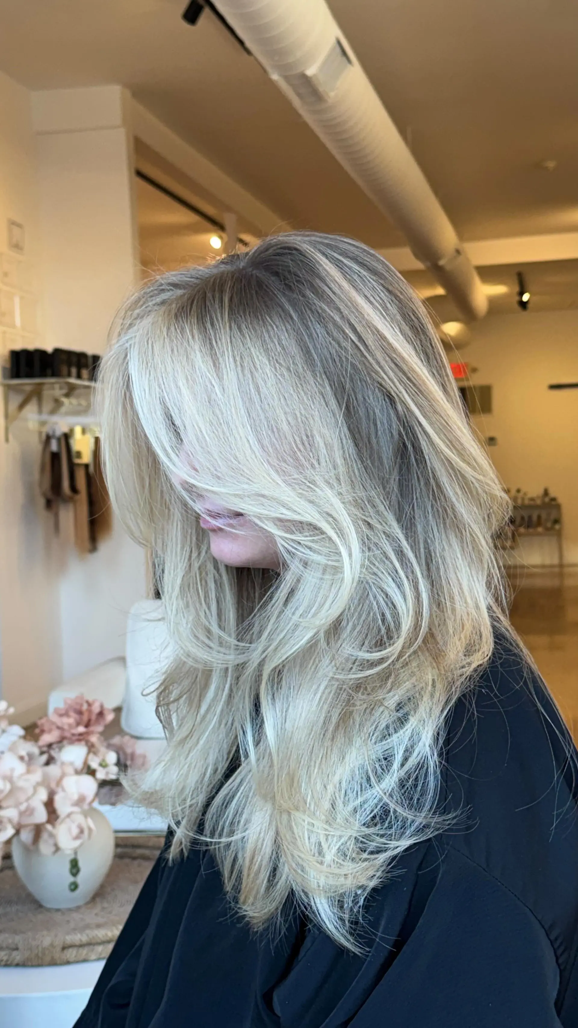 Long bright blonde hair cut with sweeping face-framing layers and styled in a big, bouncy blowout. 1