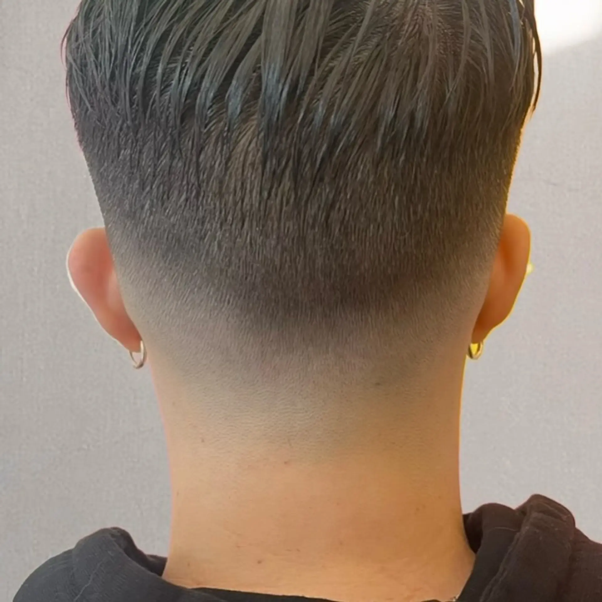 A clean low taper fade at the neckline with slicked-back textured hair on top. 1
