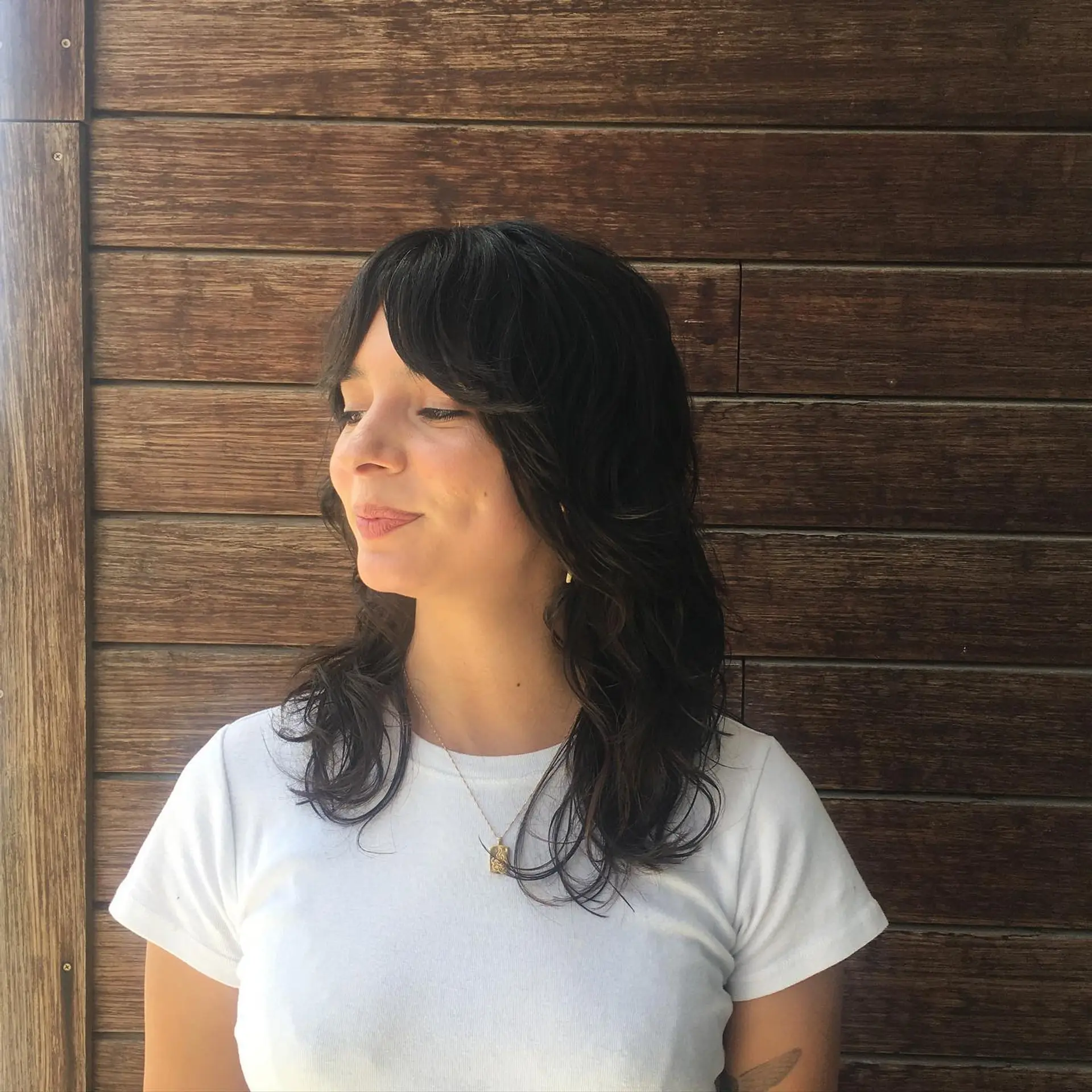 A medium-length dark shag haircut with layered textures and face-framing curtain bangs. 1