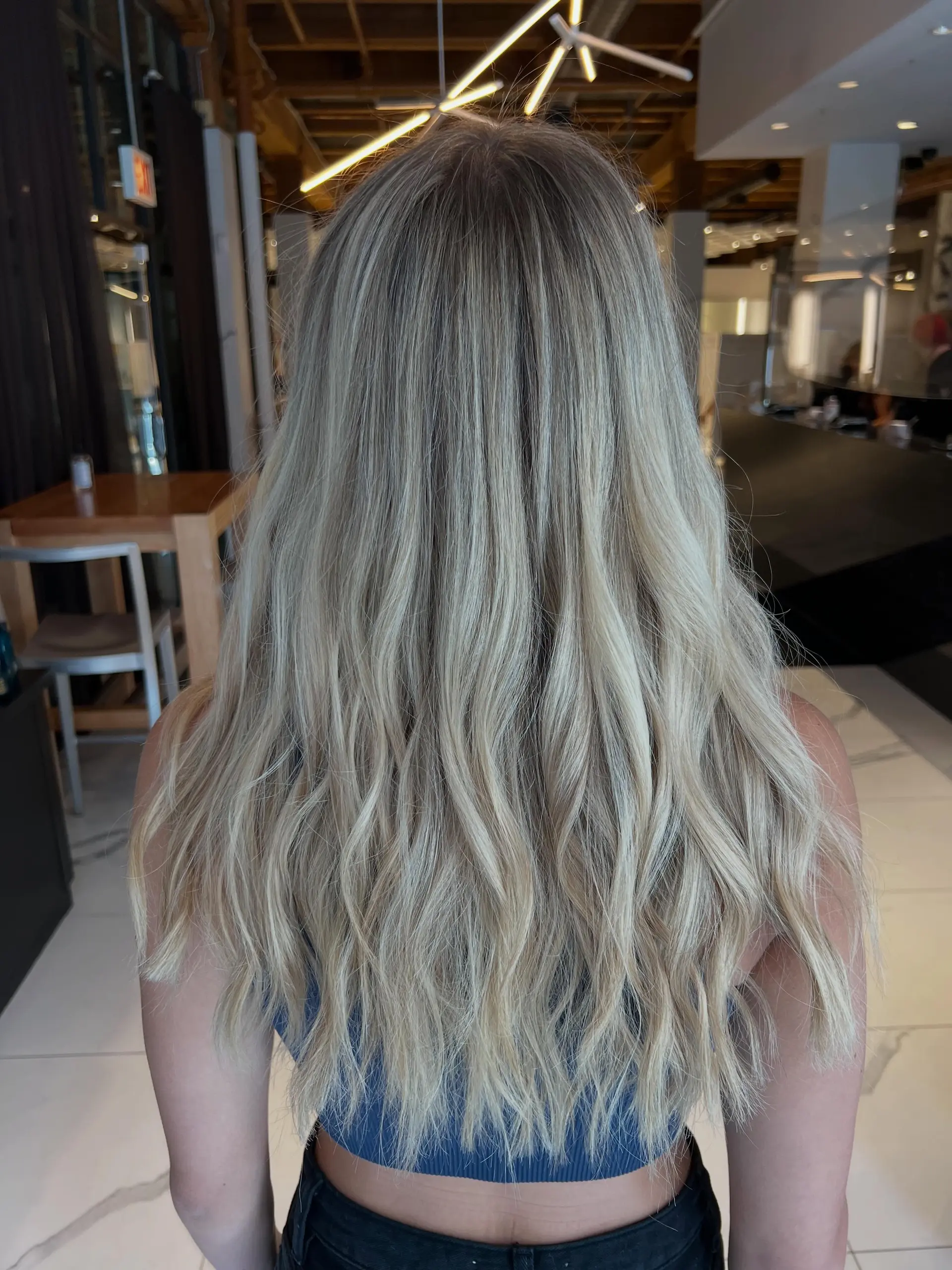 Long dimensional blonde hair styled in soft, loose waves with natural root blending. 1