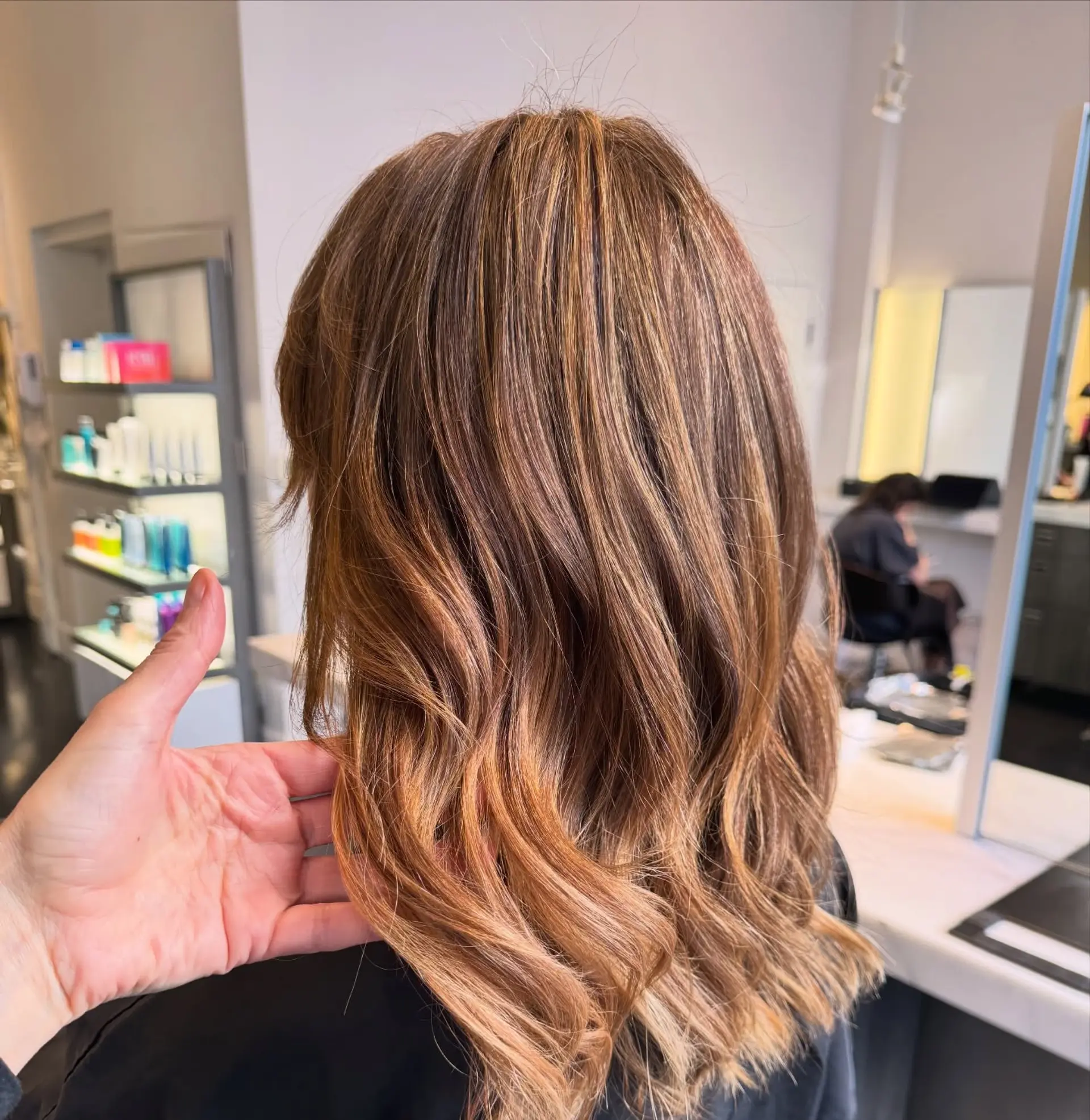 Medium-length layered haircut featuring warm golden and caramel highlights styled into soft, dimensional waves. 1