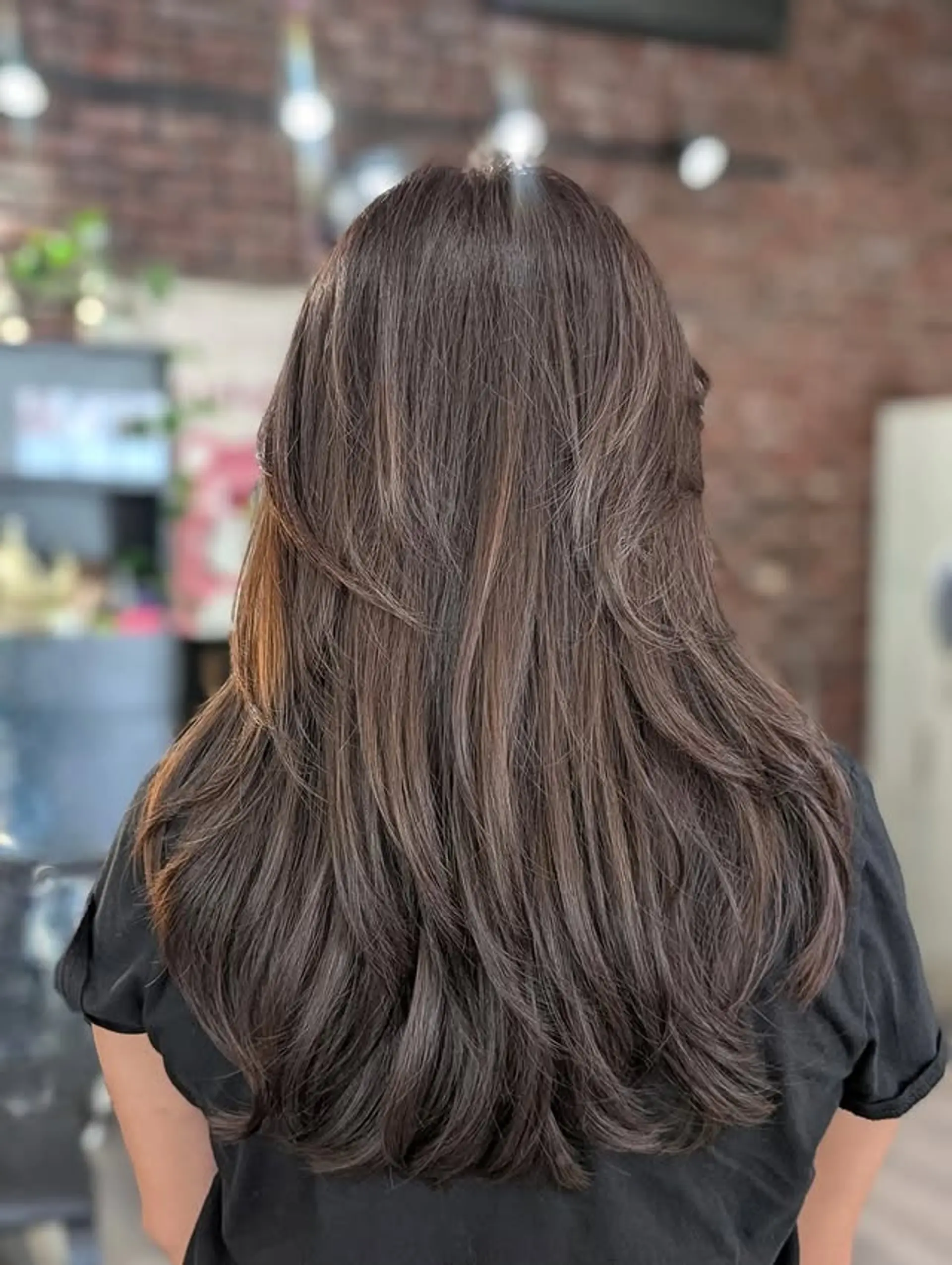 This style showcases long, flowing hair with strategically placed layers that create an abundance of volume and soft movement, especially towards the ends. The layered cut provides texture and dimension, often styled with a bouncy, curled-out finish. 1